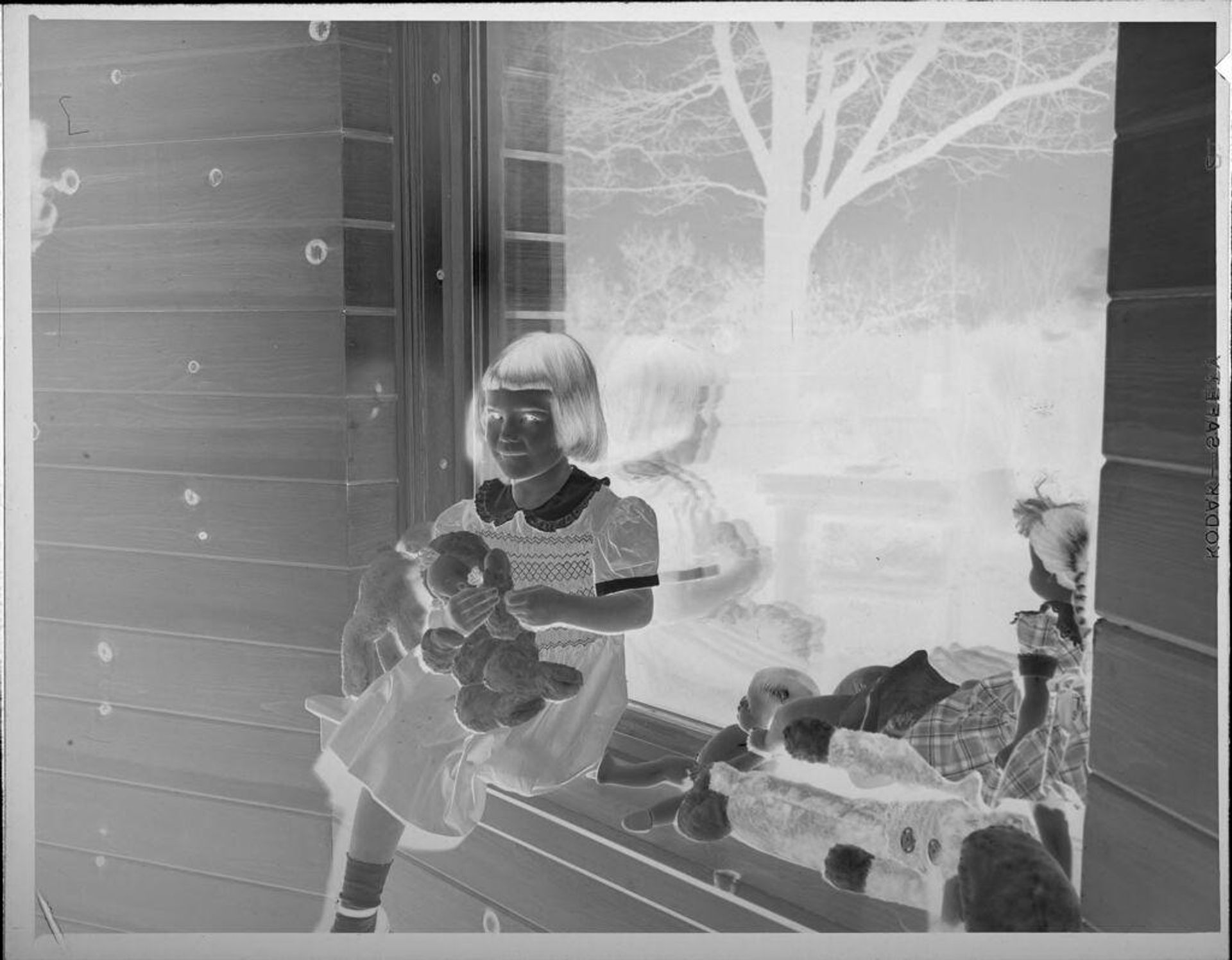 Untitled (girl sitting by window with dolls) by Lucian and Mary Brown