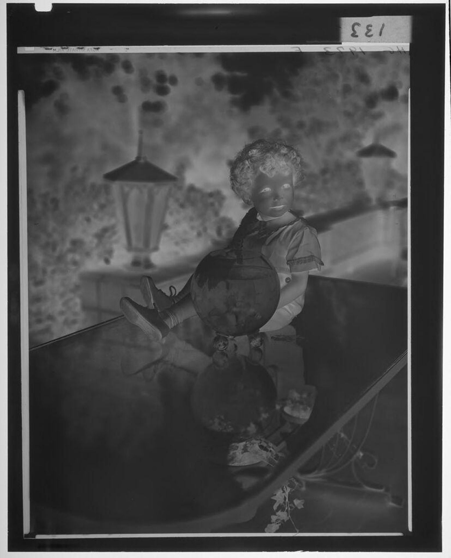 Untitled (child with fish bowl seated on table, both reflected in glass table top) by Paul Gittings
