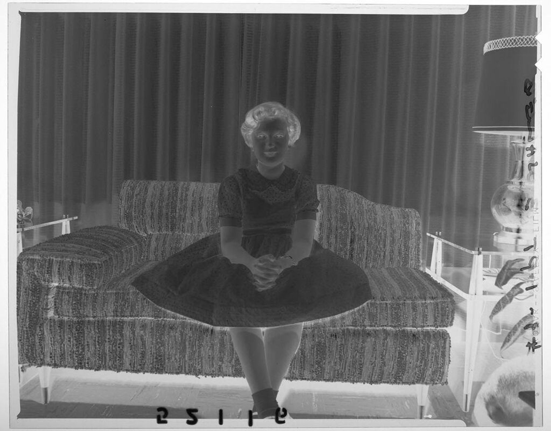 Untitled (young girl wearing dress posed sitting on couch in living room) by Martin Schweig