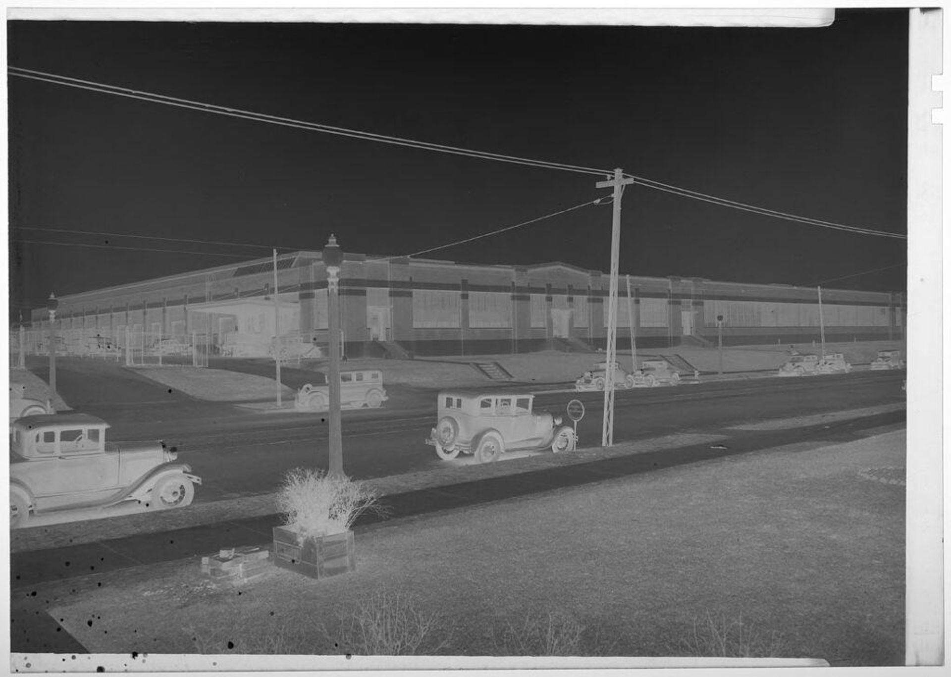 Untitled (view of town street with large building and early model cars parked) by Martin Schweig