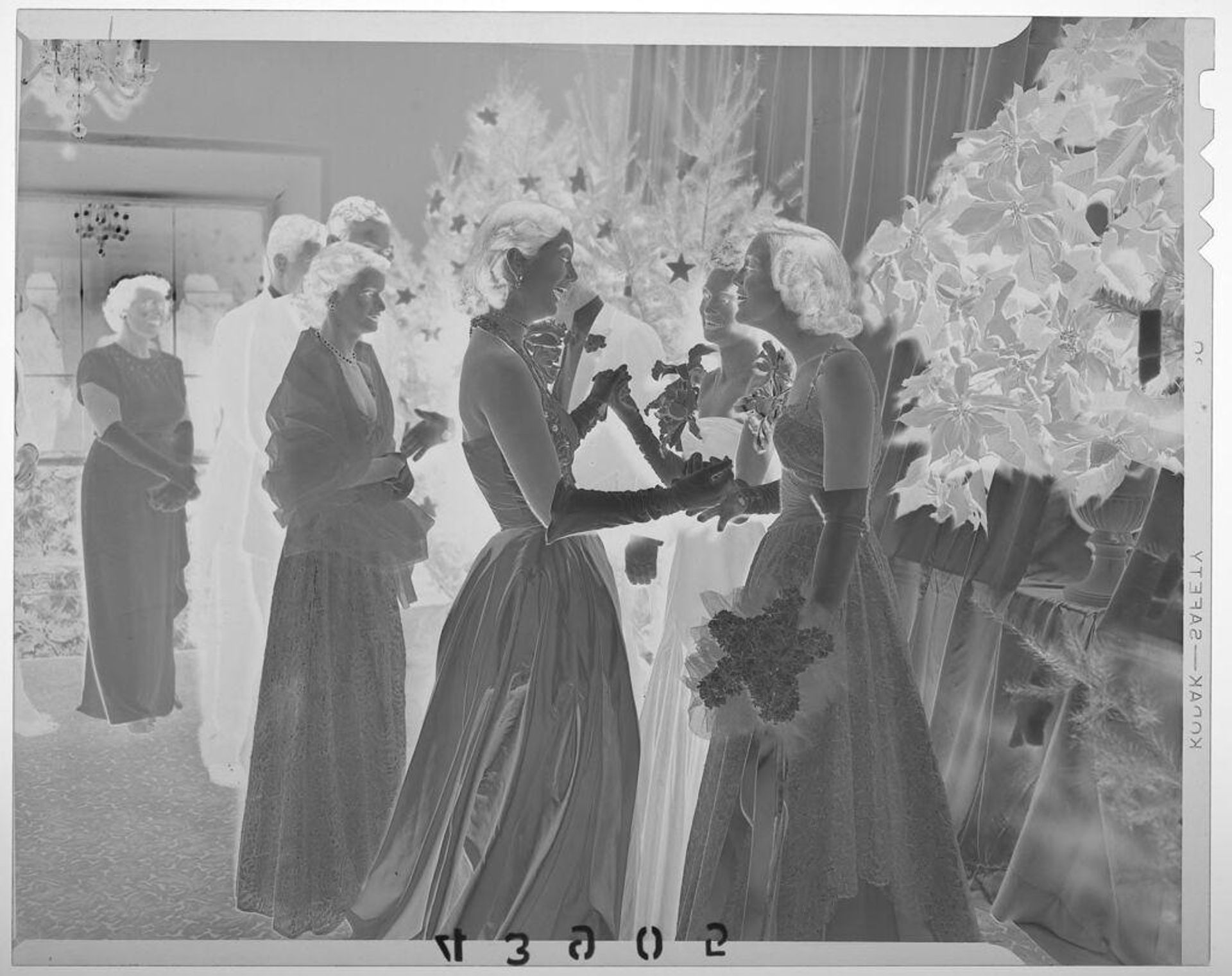 Untitled (three young women laughing and chatting at formal party with guests nearby) by Martin Schweig
