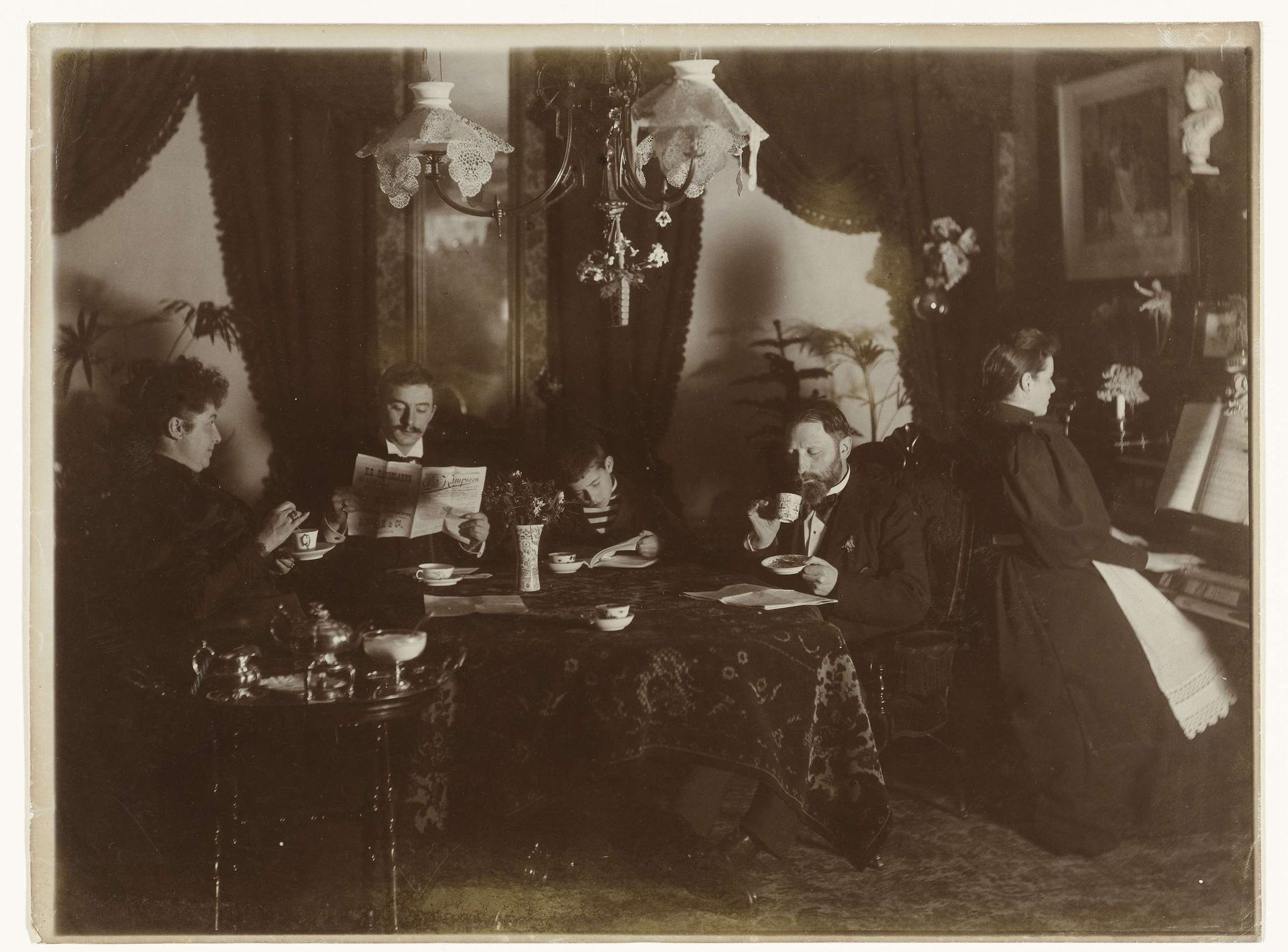 Familie aan tafel en aan de piano, thee of koffie drinkend en lezend in De Kampioen by Henri Osieck