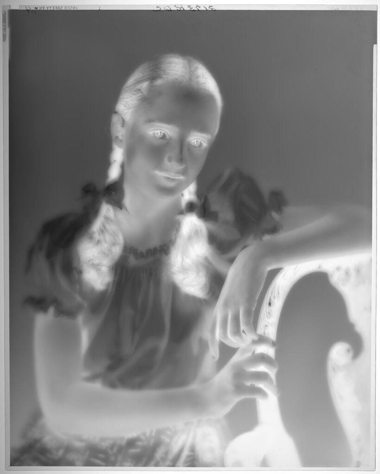 Untitled (portrait of girl in pigtail braids with one arm over back of upholstered chair) by Paul Gittings