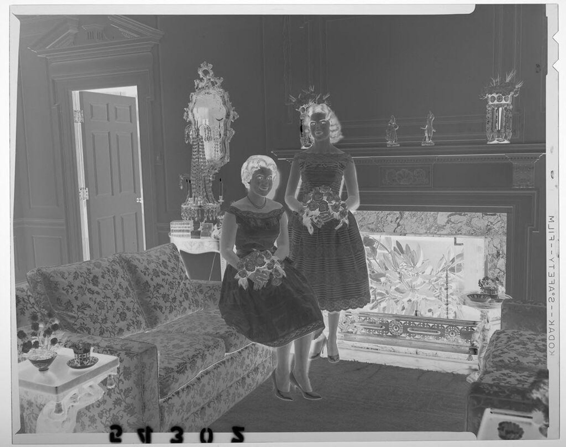Untitled (two young women holding flower bouquets posing in living room) by Martin Schweig
