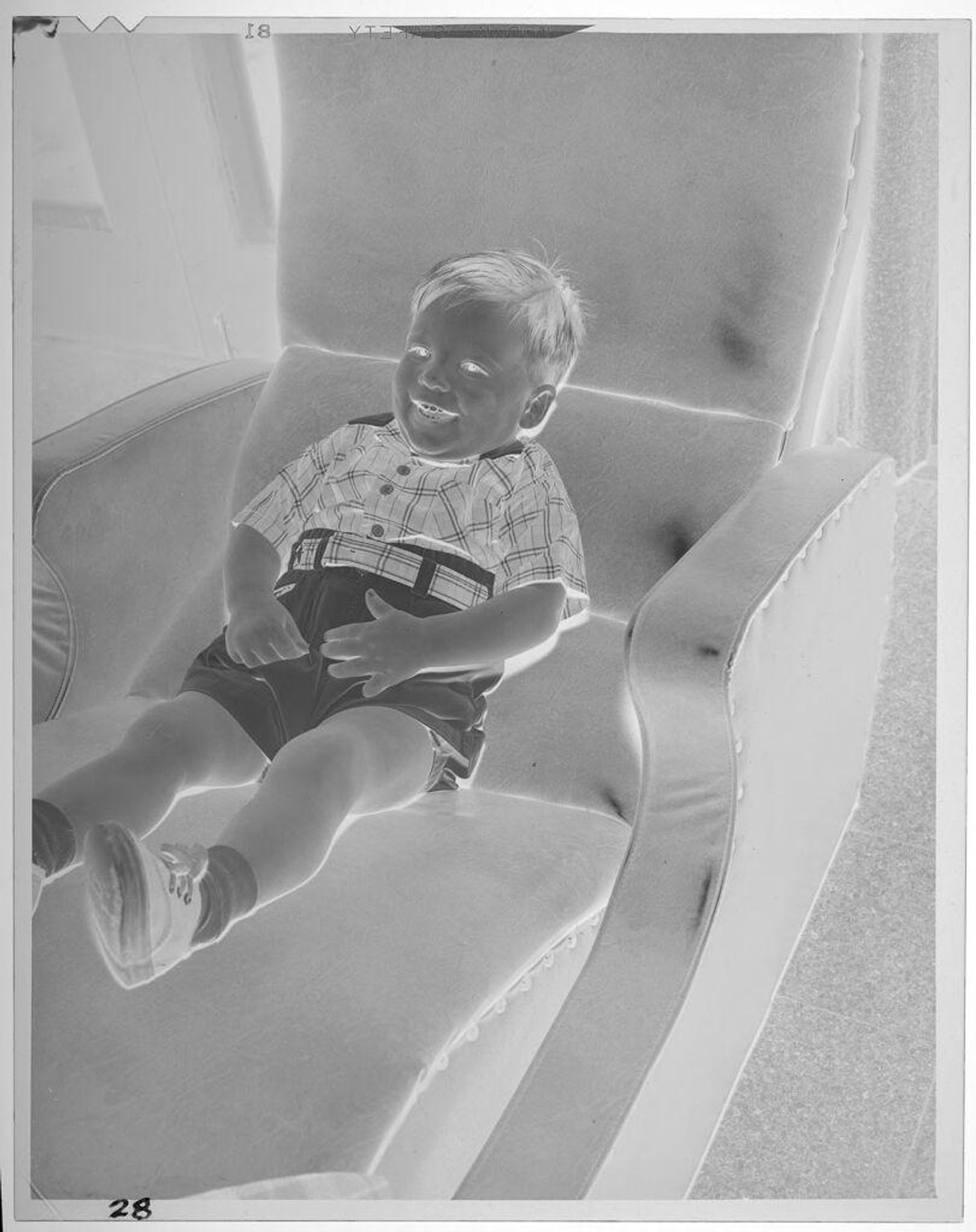 Untitled (boy sitting on reclining chair) by Lucian and Mary Brown