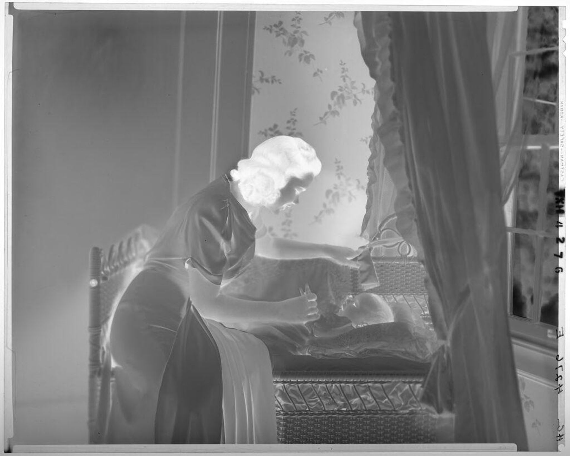 Untitled (woman leaning over baby lying in bassinet) by Paul Gittings