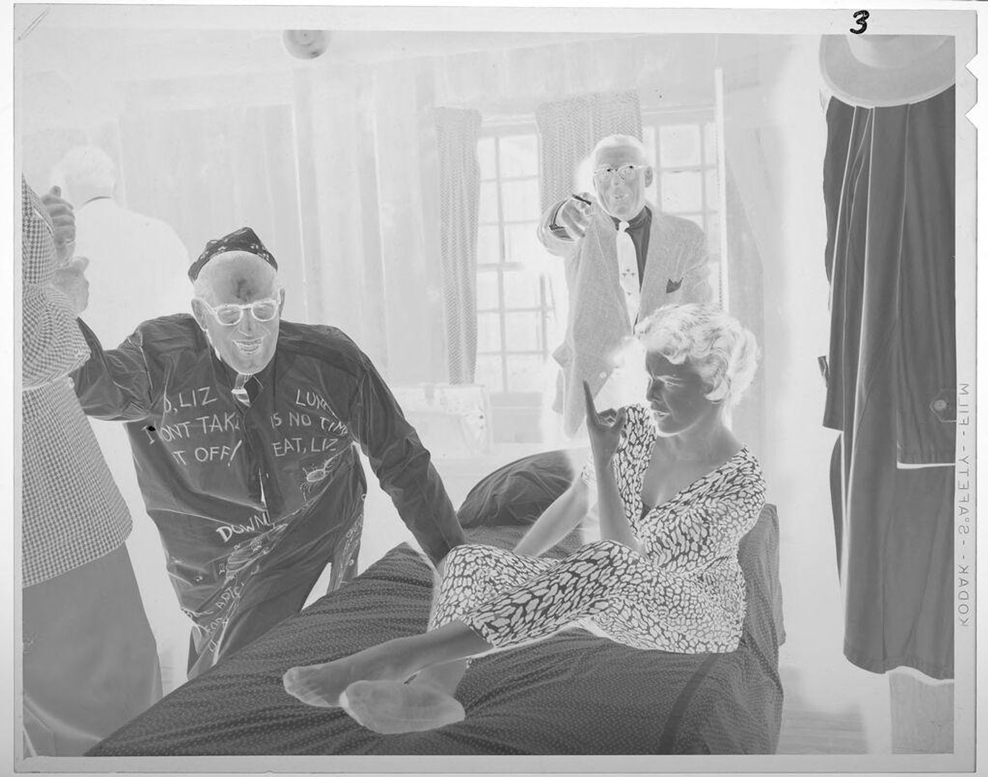 Untitled (woman in leopard-print outfit on bed, men around) by Lucian and Mary Brown