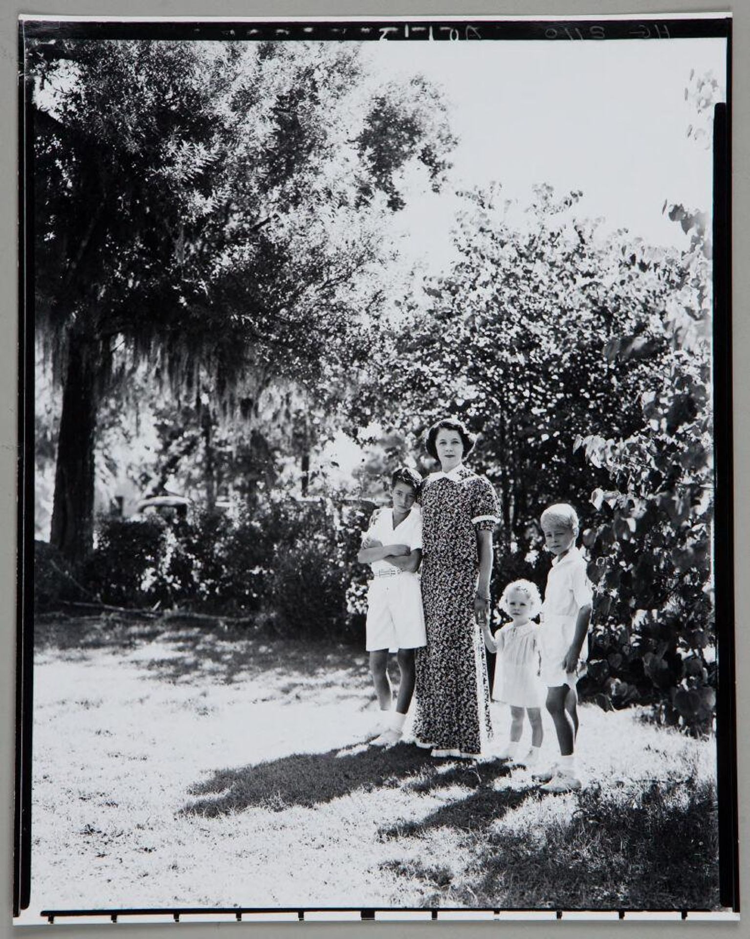 Untitled (mother standing in yard with two boys and little girl, children dressed in white) by Paul Gittings