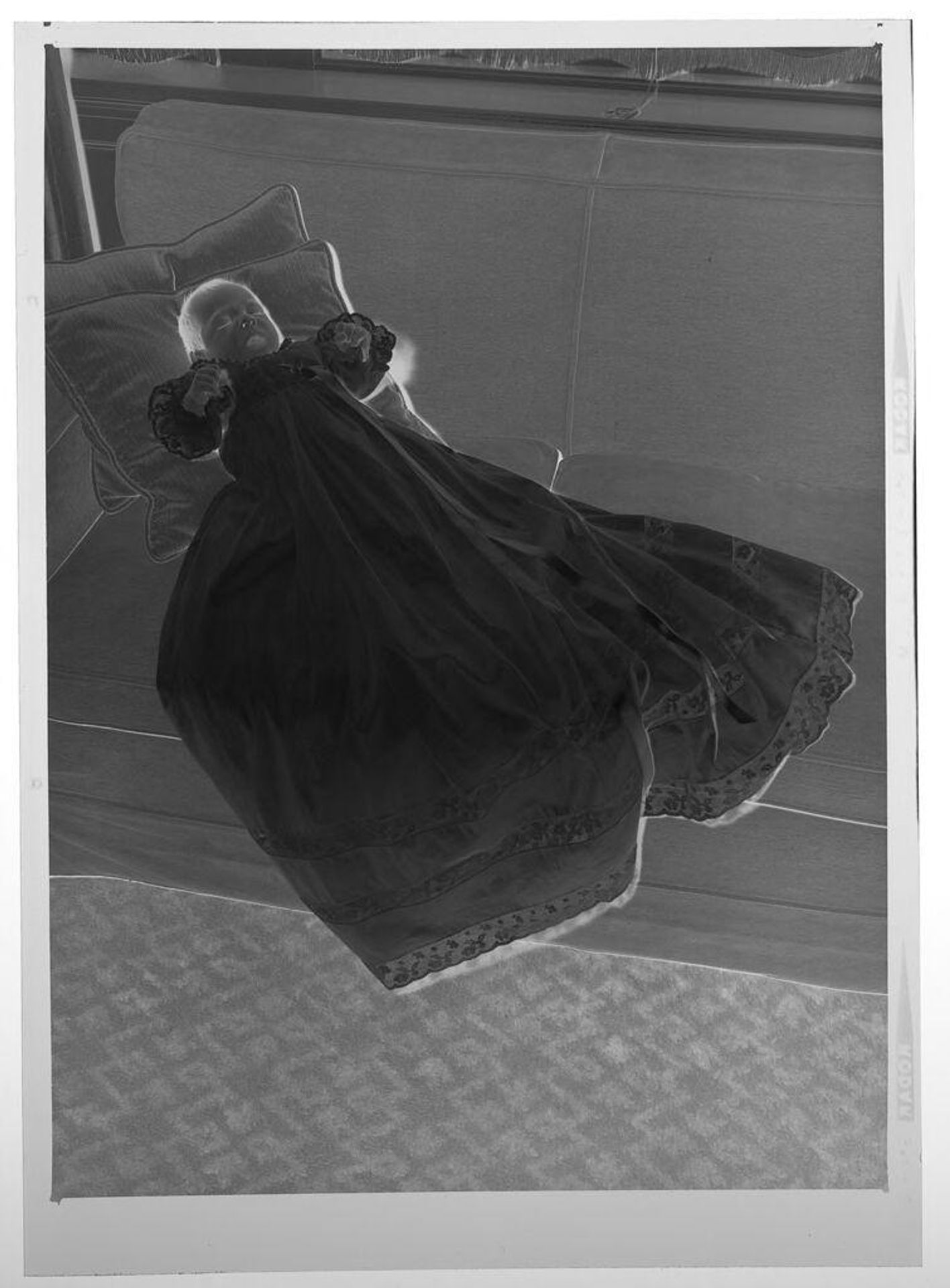 Untitled (small baby in long dress posed lying on couch) by Martin Schweig
