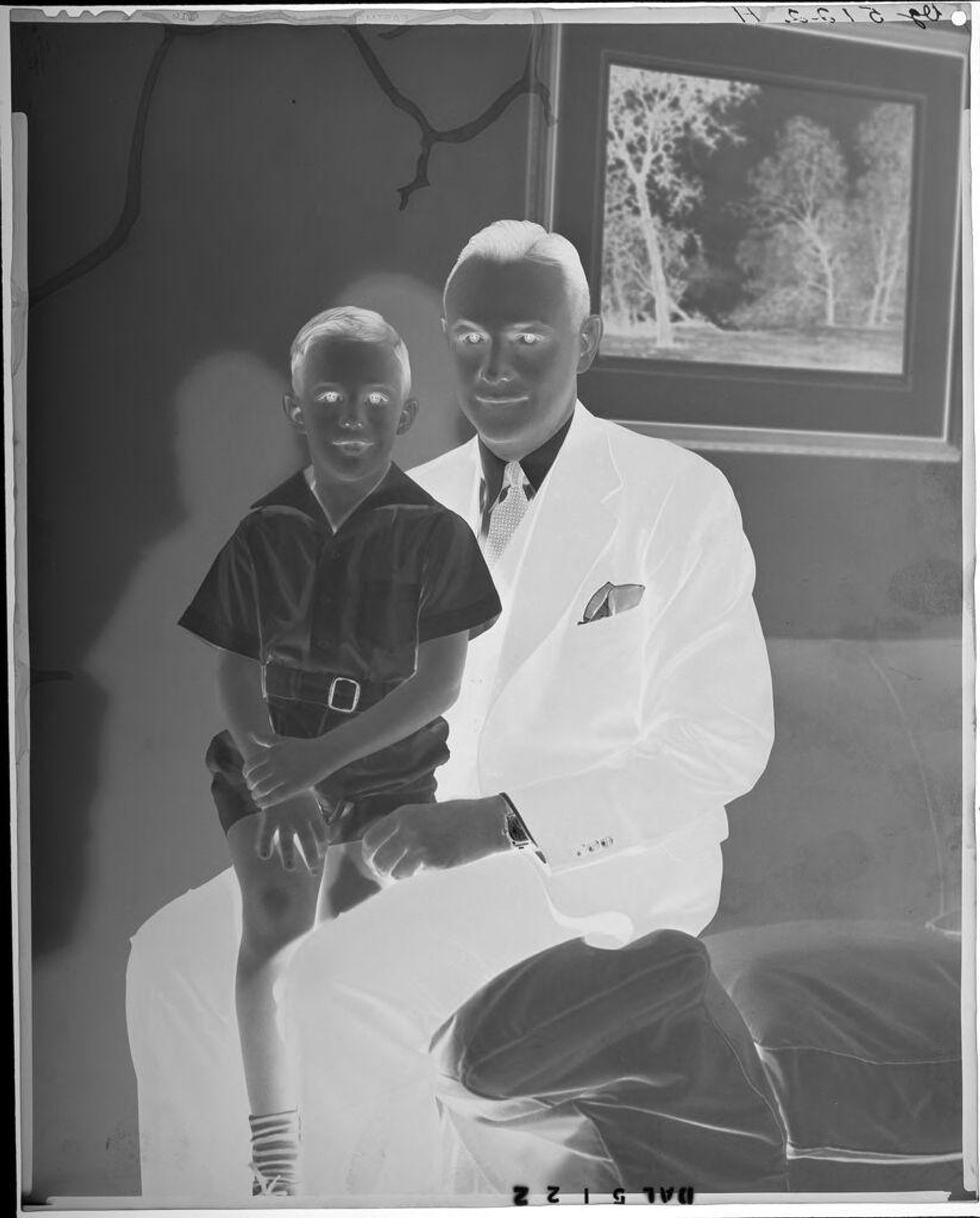 Untitled (father in suit seated with son on edge of sofa) by Paul Gittings