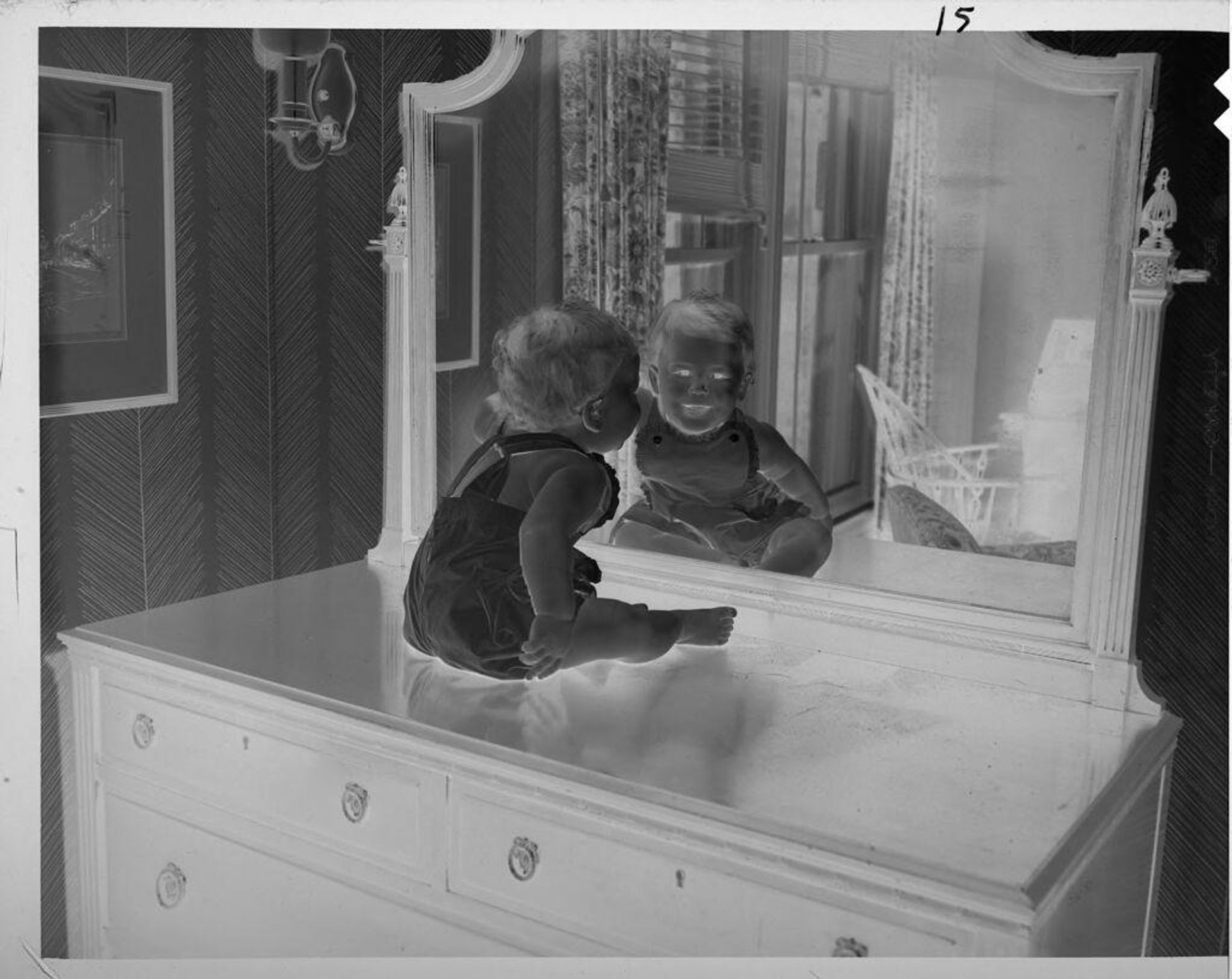 Untitled (baby sitting on bureau looking into mirror) by Lucian and Mary Brown