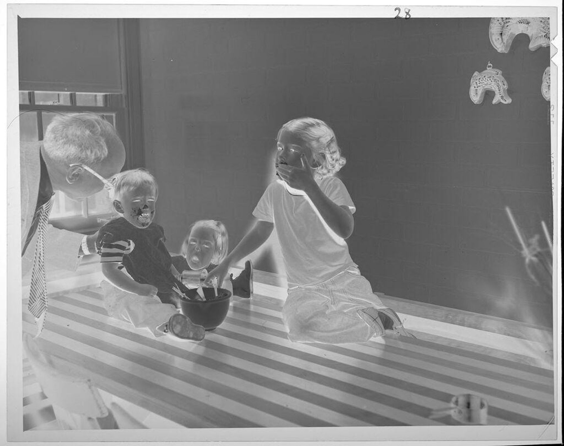 Untitled (kids eating batter from bowl, boy crying) by Lucian and Mary Brown