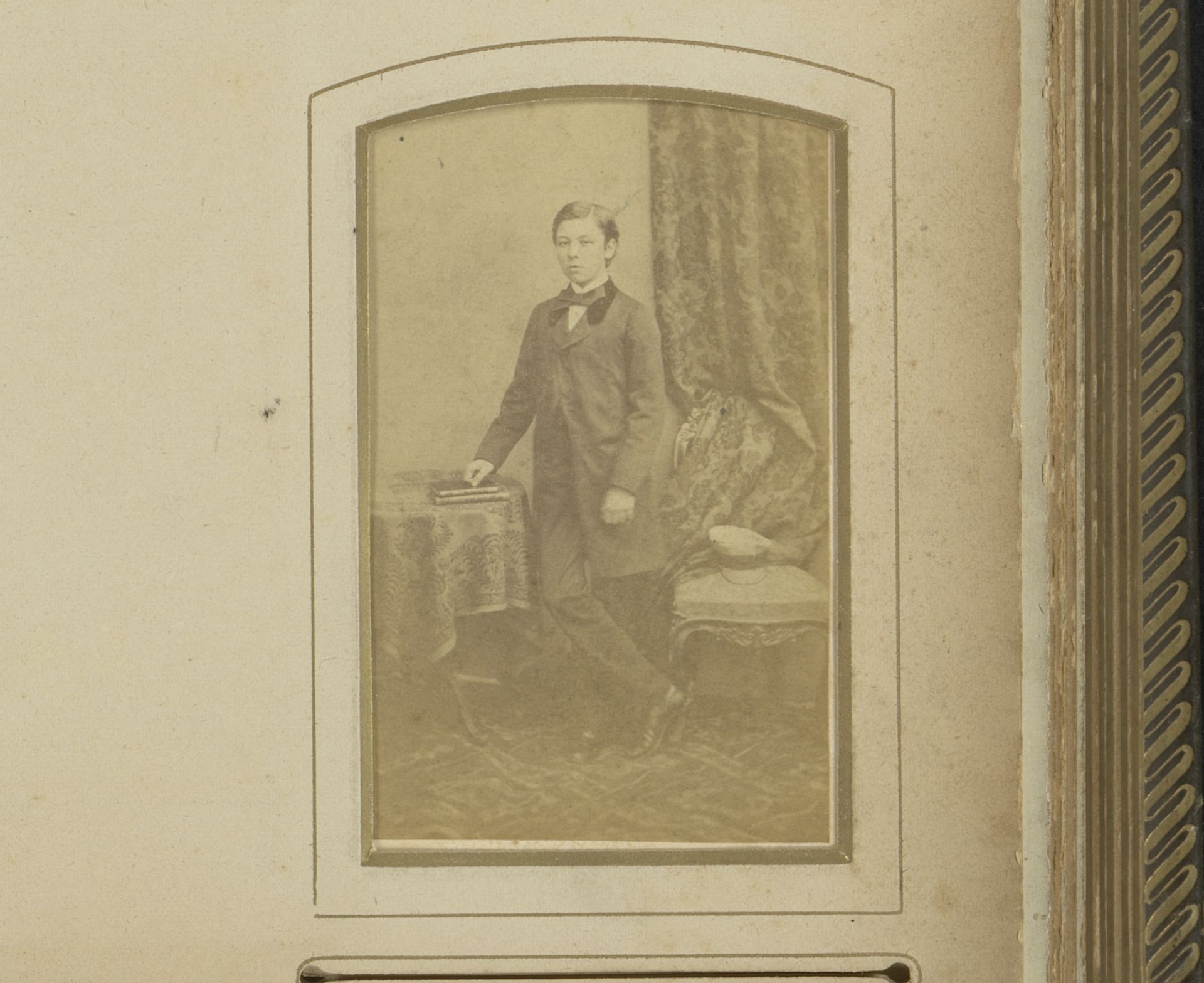 Portret van een jongen in lange jas, staand bij een tafel met boeken by Henri Blanckart