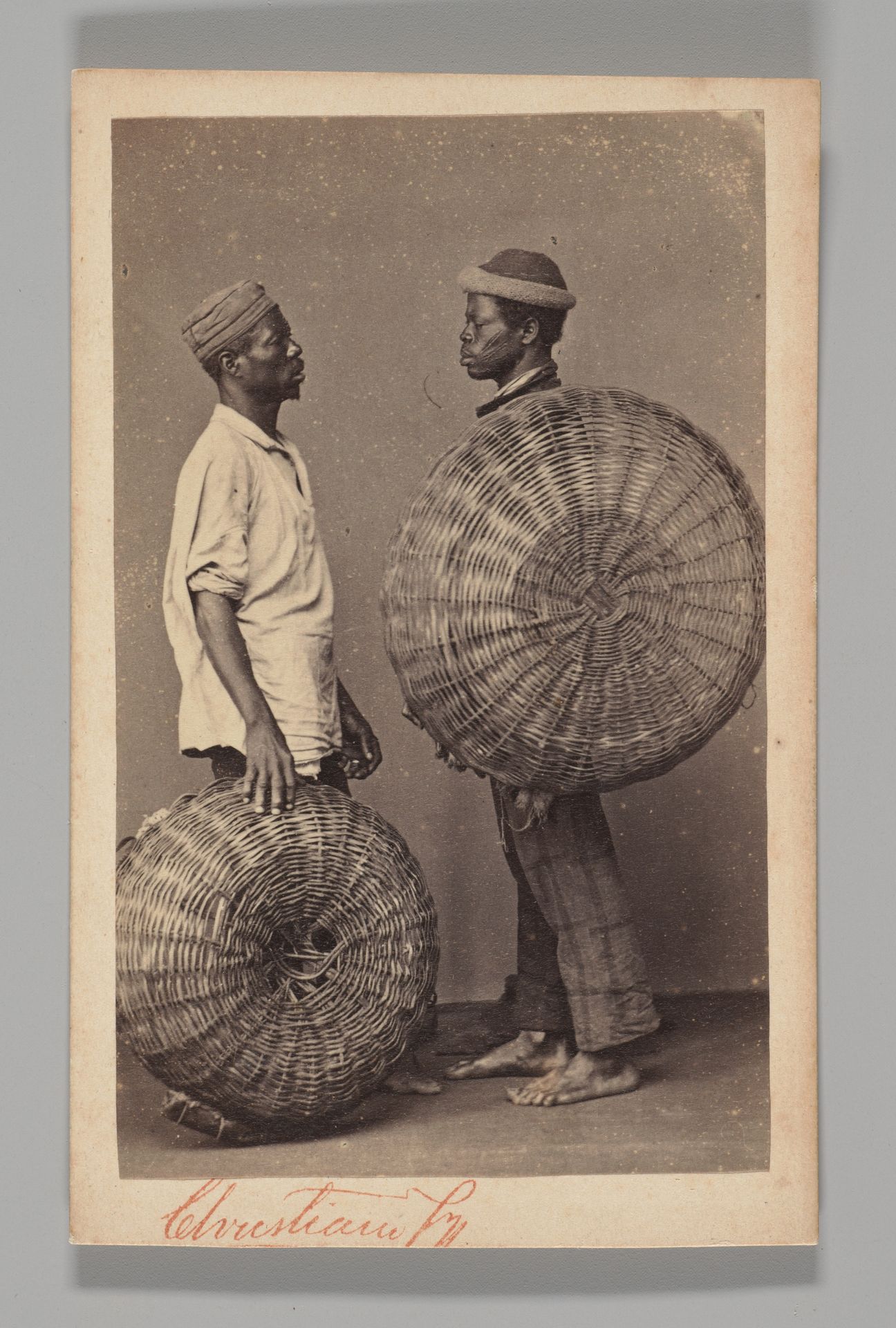 [Studio Portrait: Two Male Street Vendors in Profile with Baskets, Brazil] by Christiano Junior