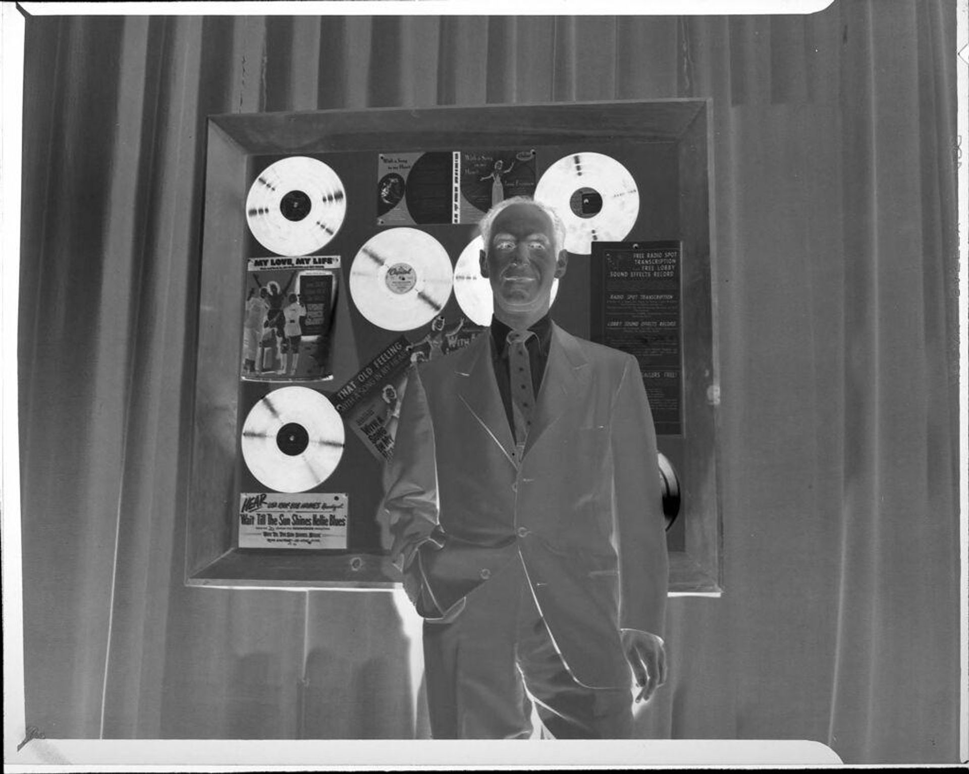 Untitled (man in front of records on wall) by Peter James Studio