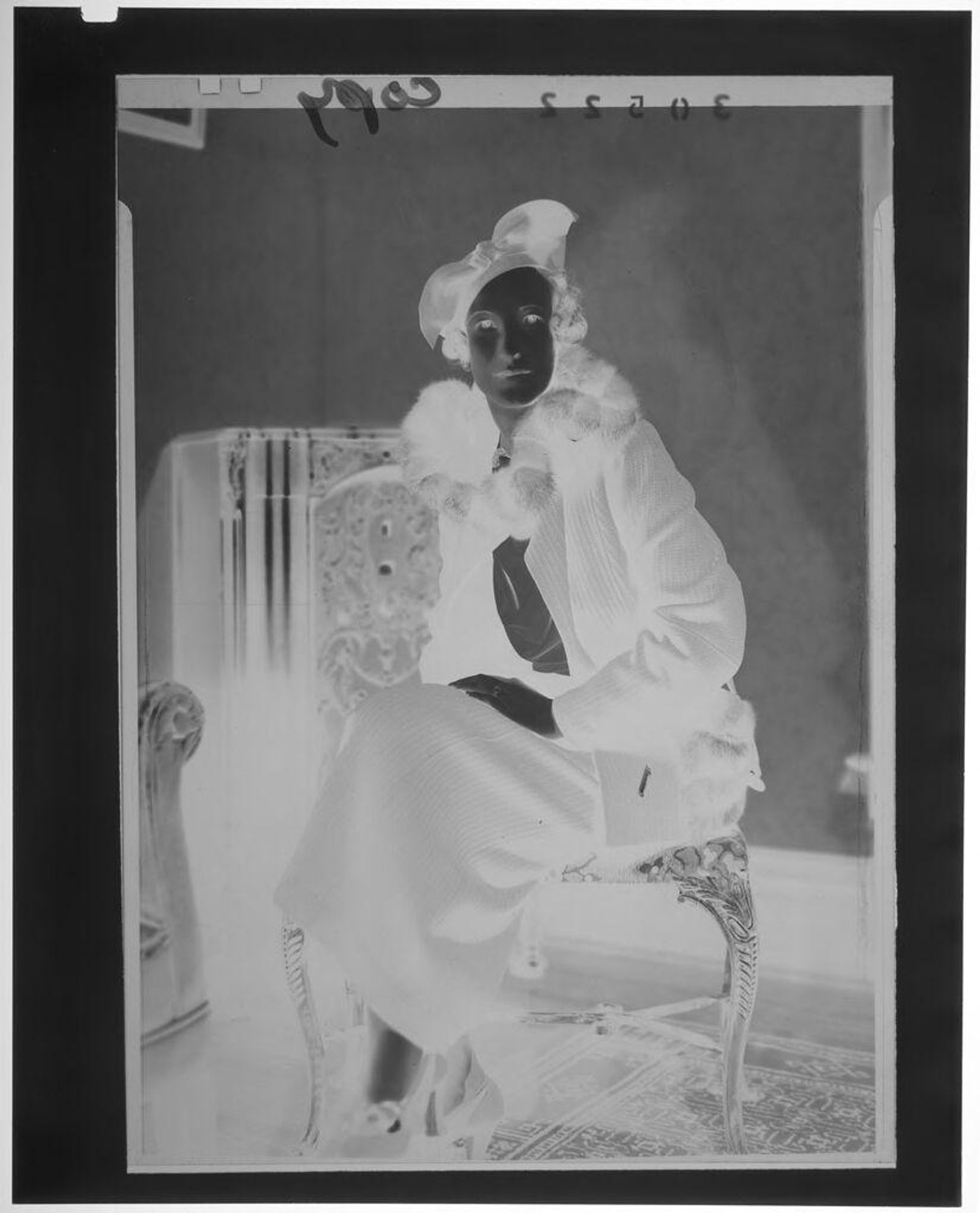 Untitled (portrait of woman wearing hat with bow and coat with fur collar sitting in elegant chair) by Martin Schweig