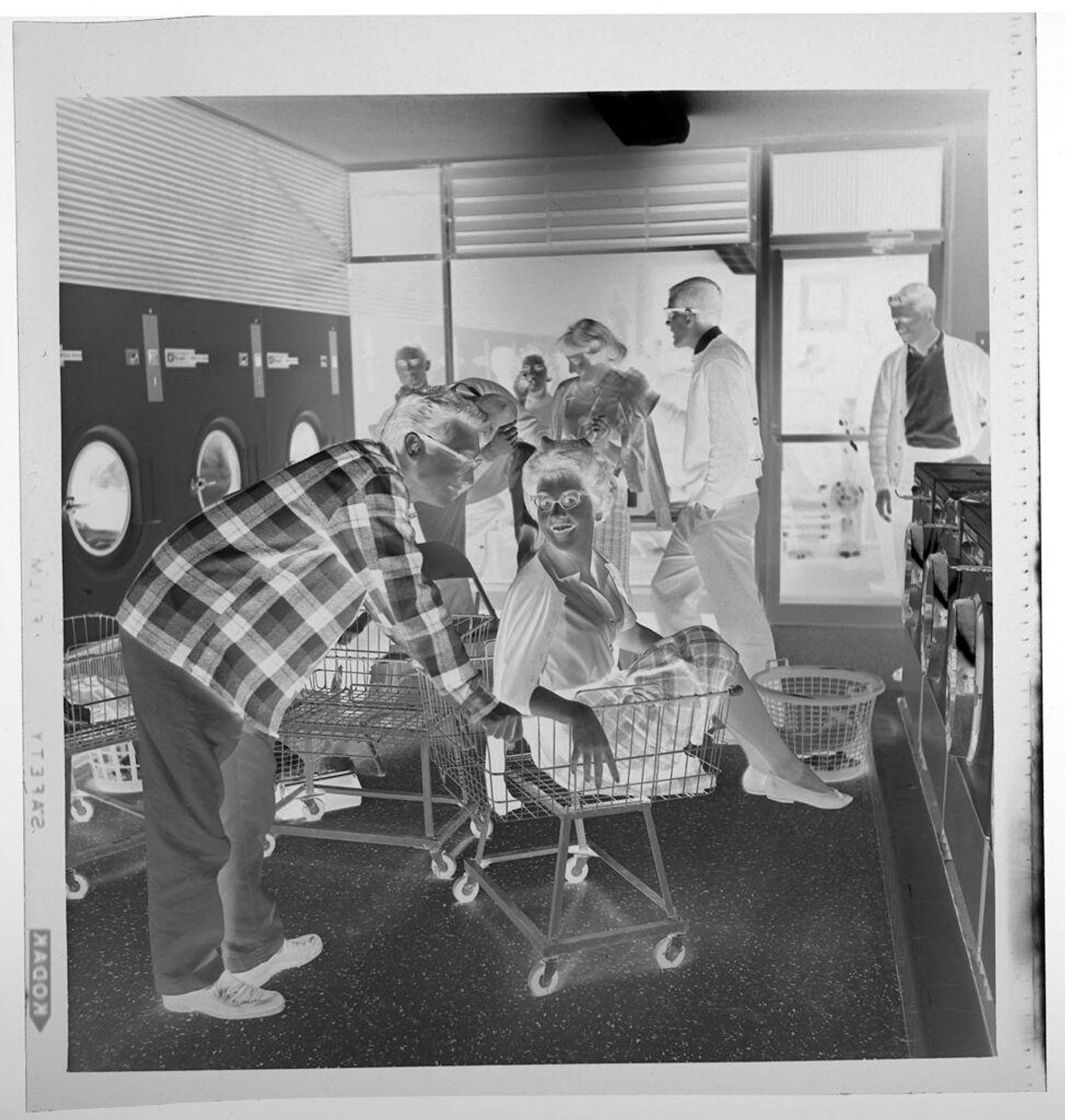 Untitled (party in laundromat, woman being pushed in cart) by Jack Gould