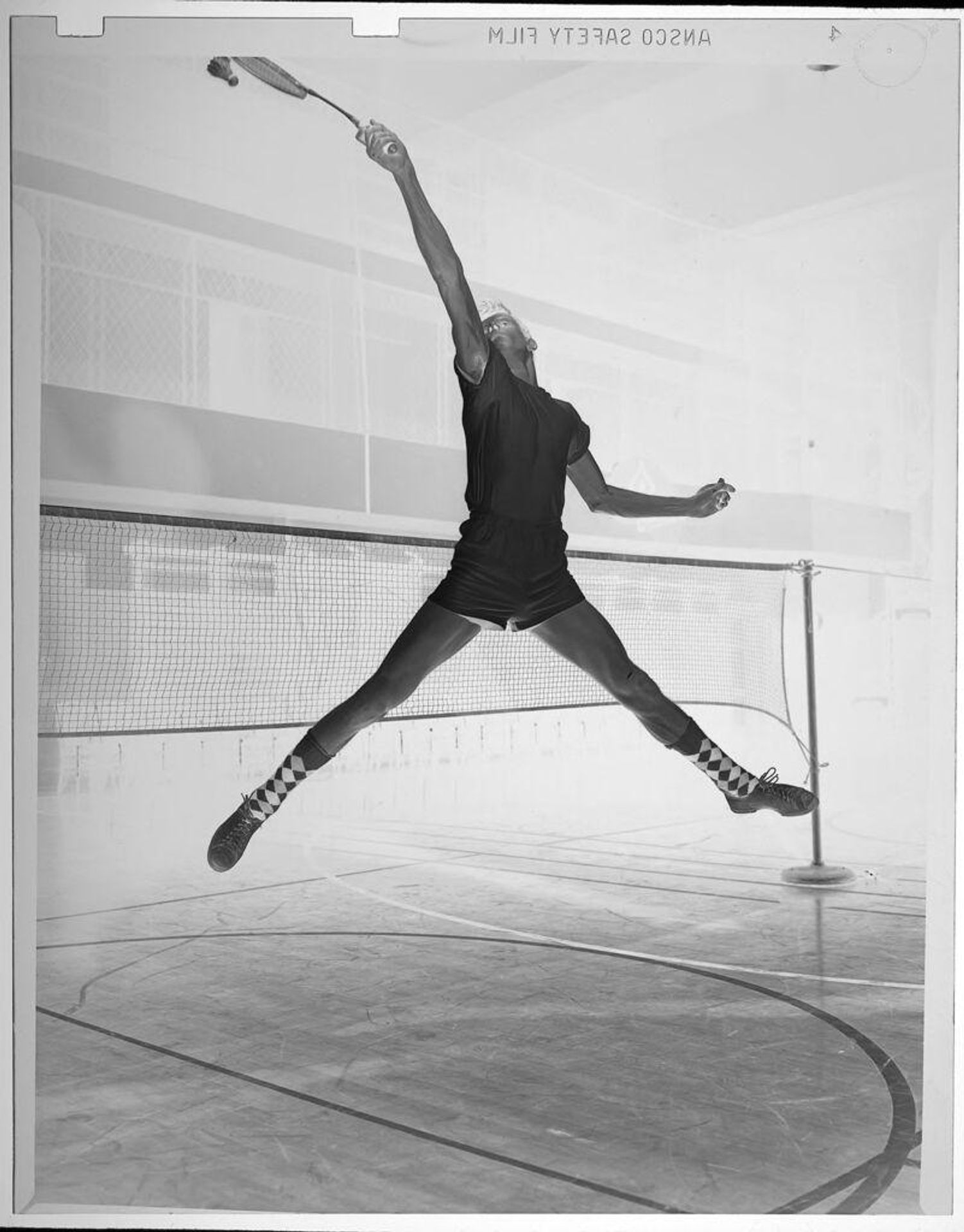 Untitled (man playing indoor badminton, leaping to hit shuttlecock) by Jack Gould
