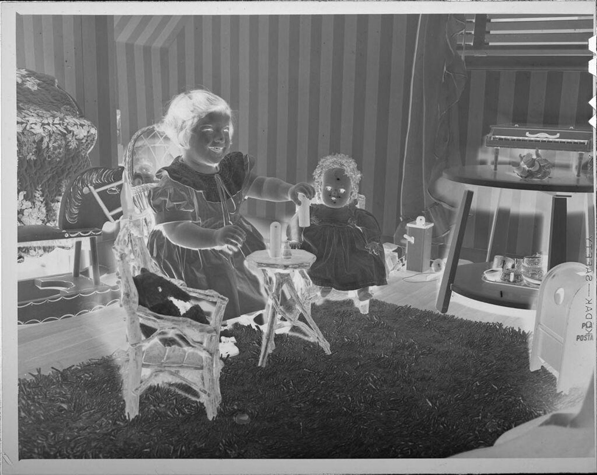 Untitled (girl sitting in chair with dolls) by Lucian and Mary Brown