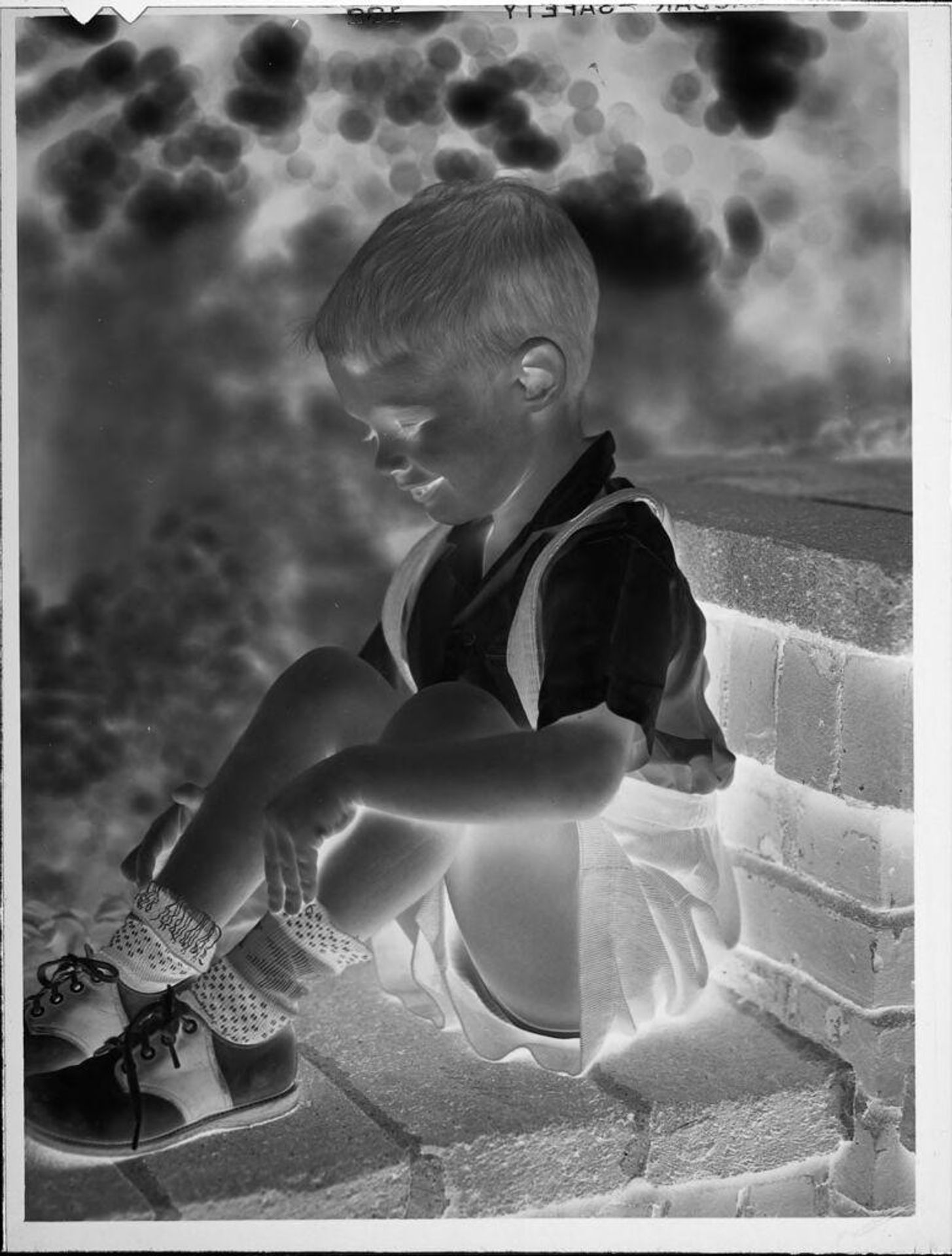 Untitled (boy sitting on brick wall) by Lucian and Mary Brown