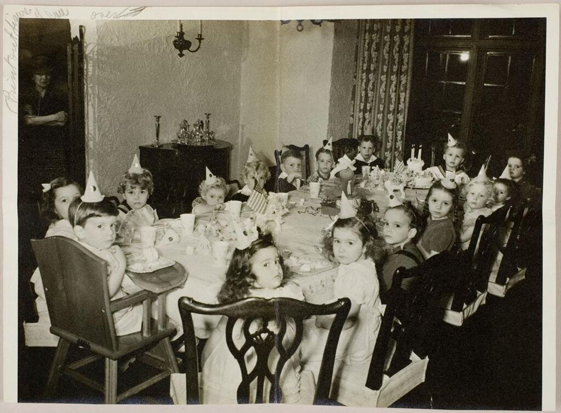 Untitled (children seated around birthday party table with woman standing in doorway of room) by Martin Schweig