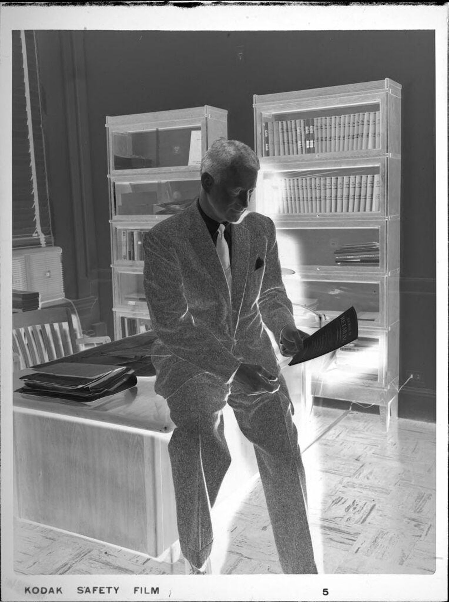 Untitled (man leaning on desk, reading) by Peter James Studio