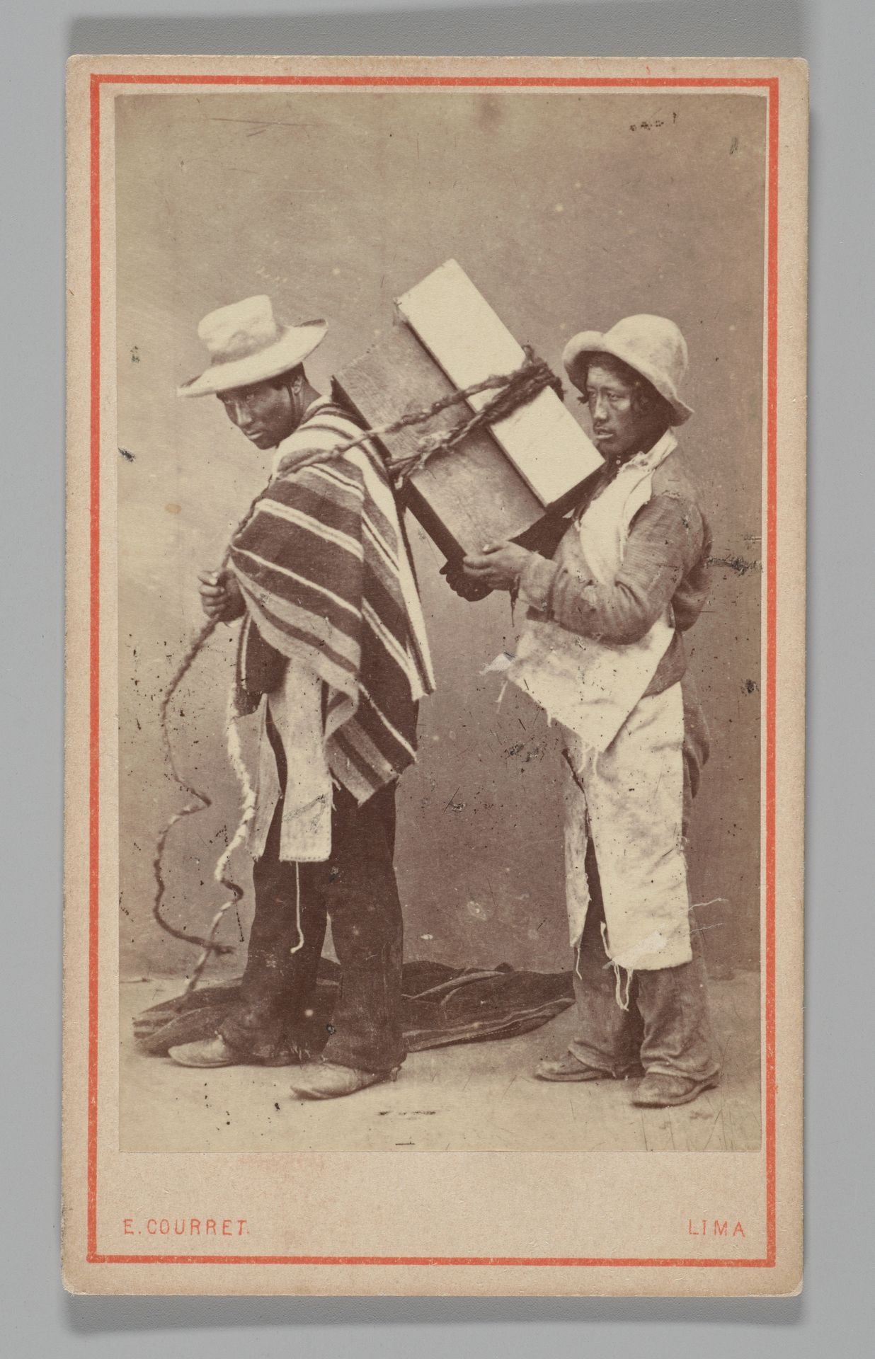 [Studio Portrait: Two Men, one with Box Tied to his Back, Lima] by Eugenio Courret