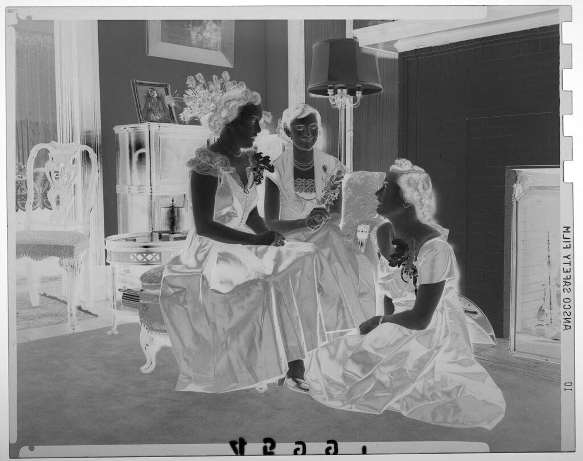 Untitled (three young women in formal dresses posed chatting in fancy room with fireplace) by Martin Schweig
