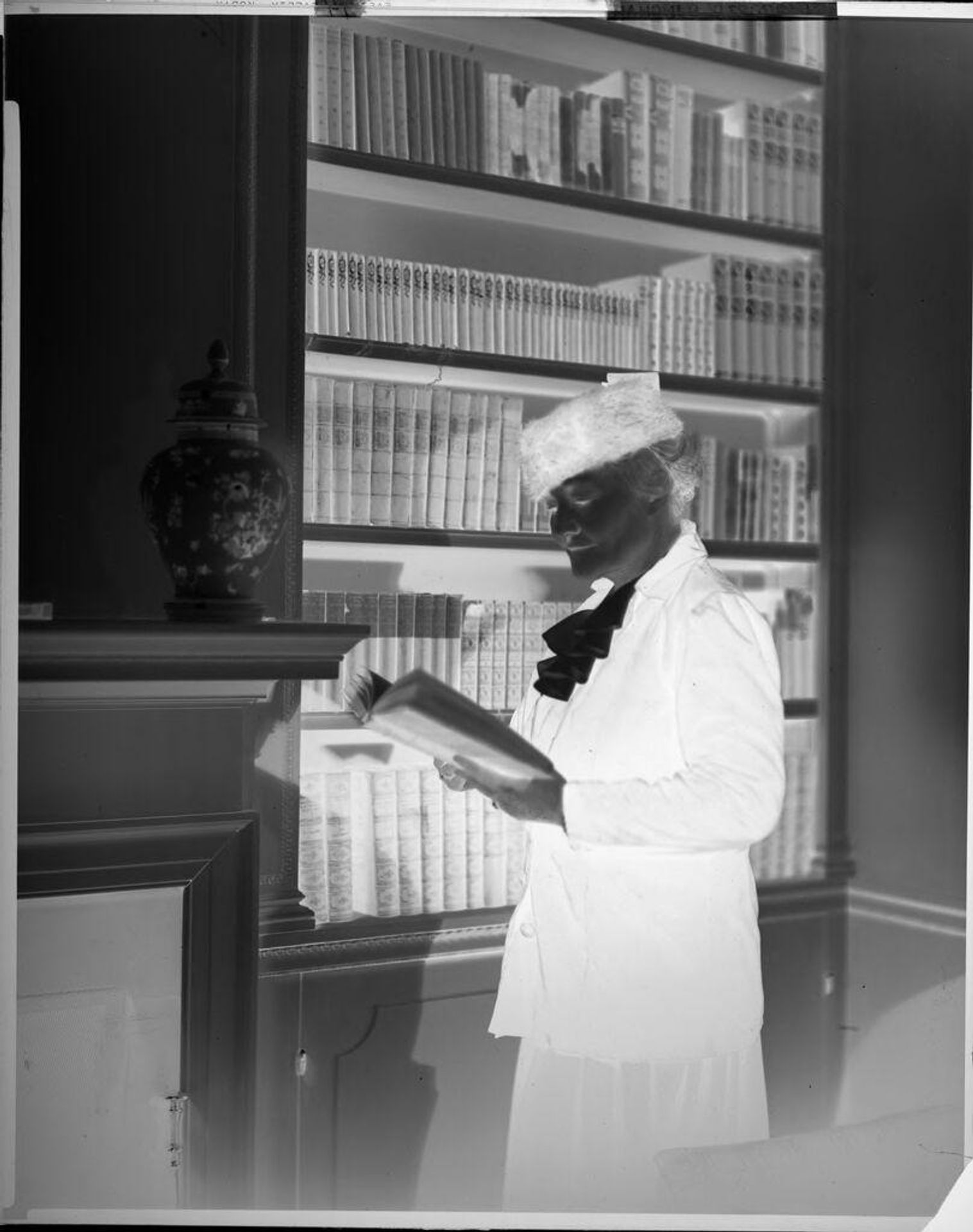 Untitled (woman in hat, posed reading in library) by Harris & Ewing