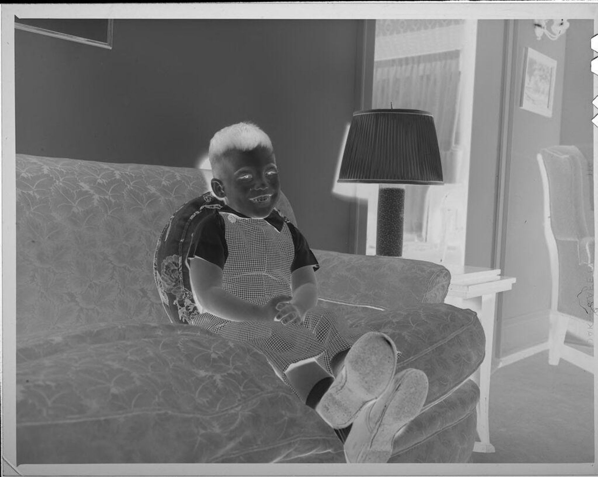 Untitled (smiling boy sitting on couch) by Lucian and Mary Brown