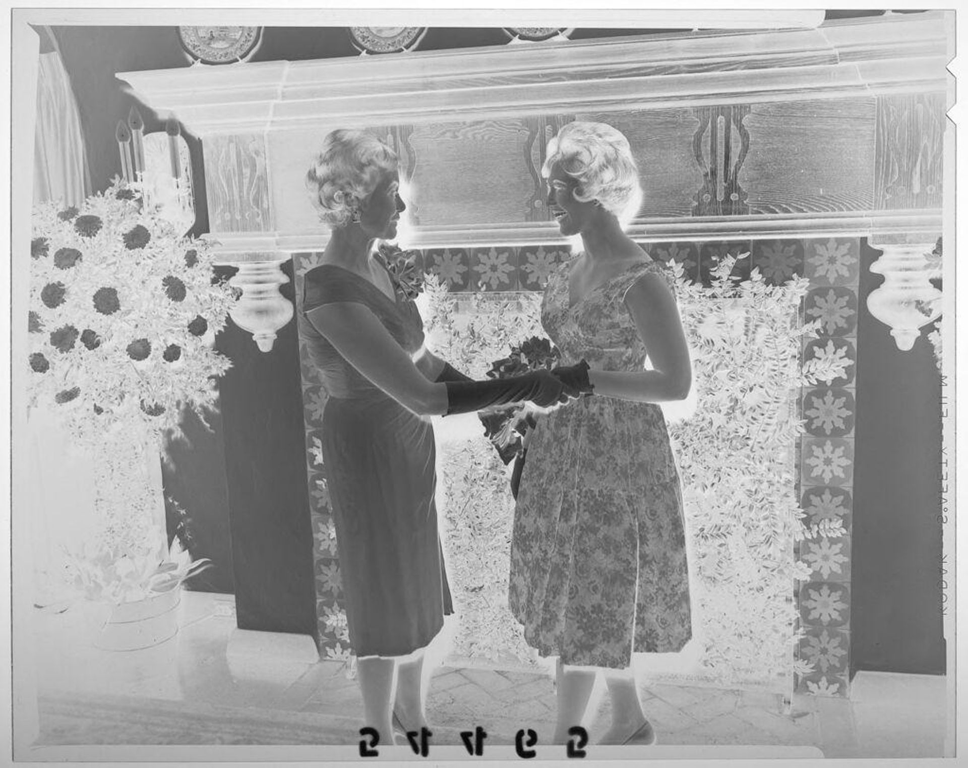 Untitled (young woman and mother posed looking at one another in front of fireplace at debutante party) by Martin Schweig