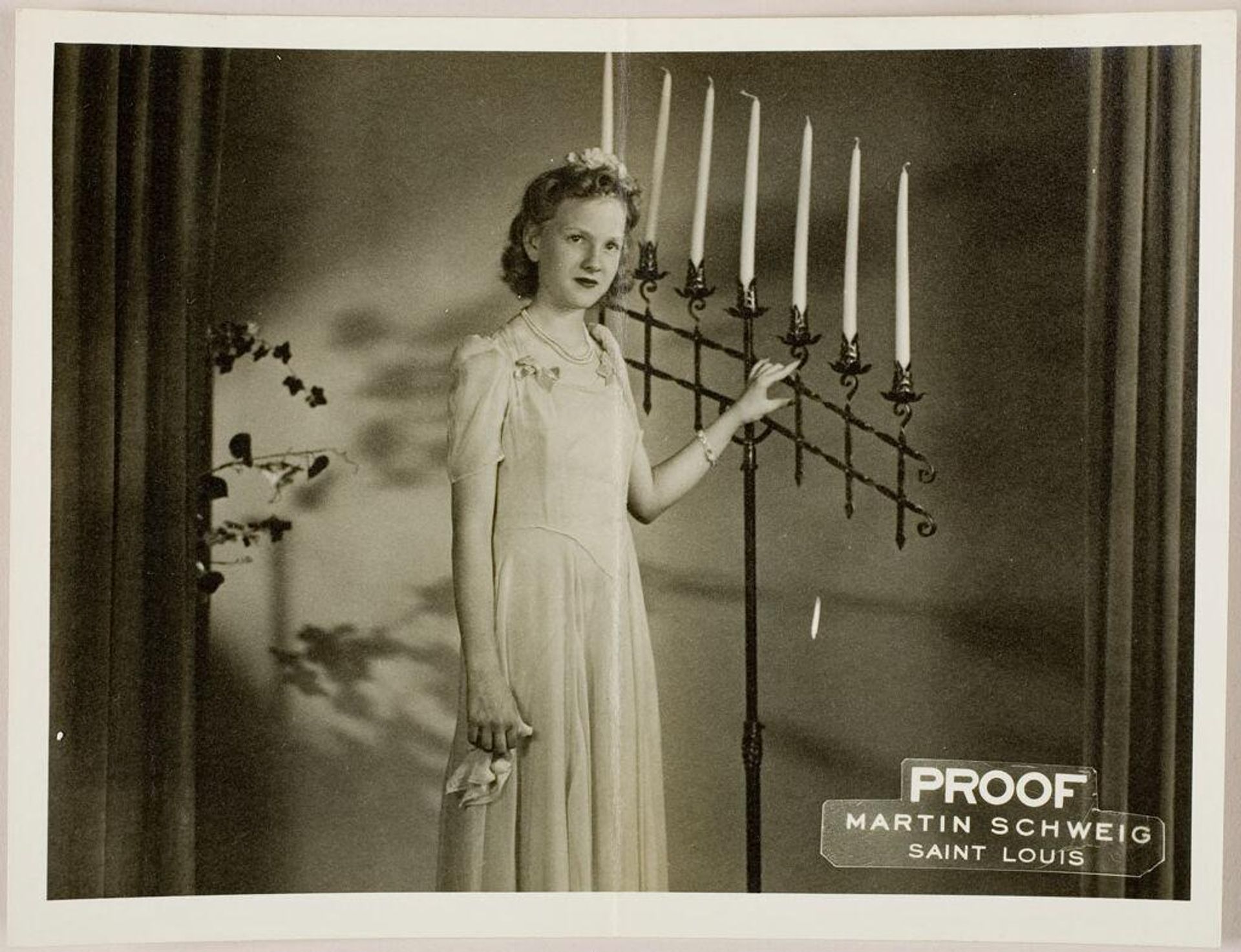 Untitled (young woman posed standing next to large candelabra between curtains) by Martin Schweig