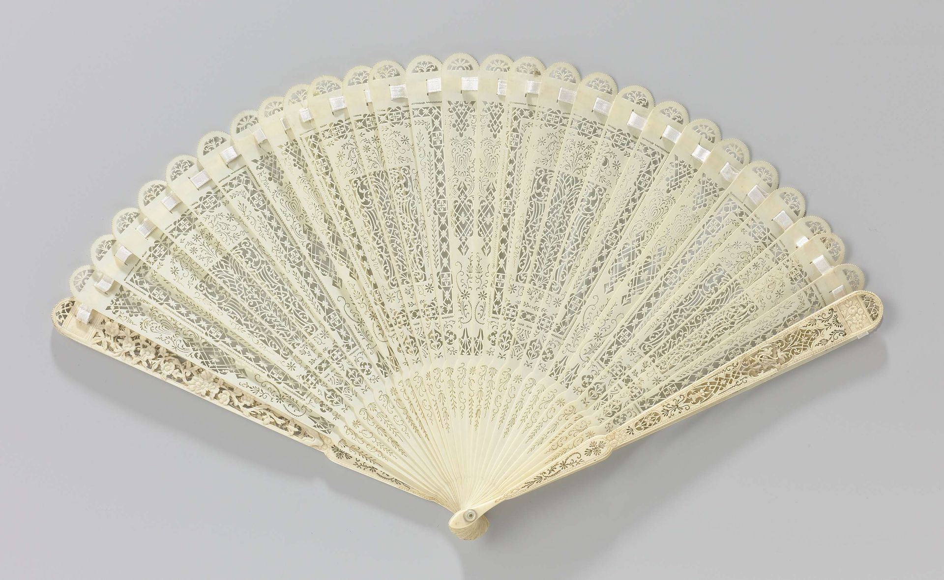 Brisé-waaier van gesneden ivoor met symmetrisch opgebouwd patroon en op de sluitbenen een huwelijksaltaar onder twee vogels bij een trofee by Anonymous