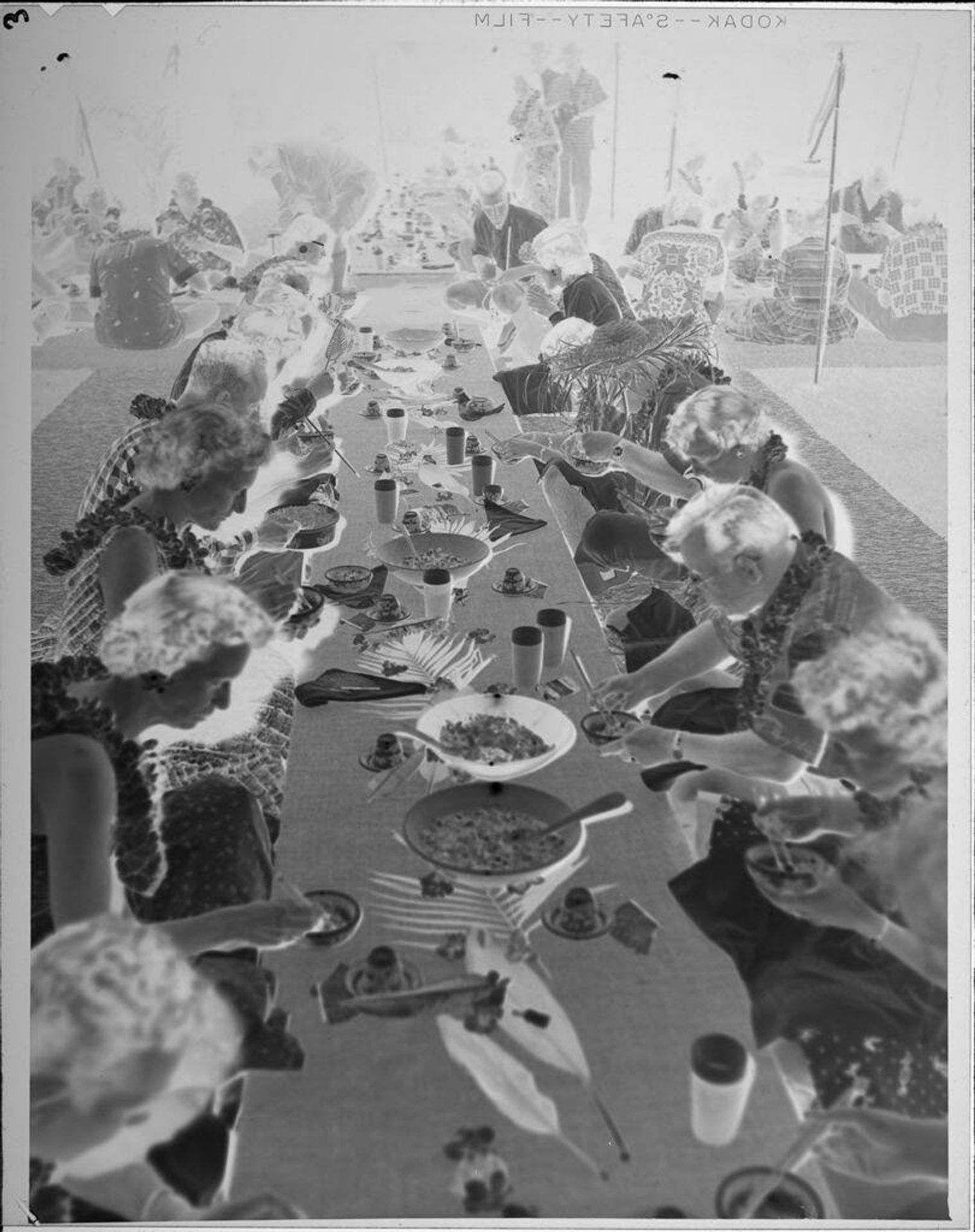 Untitled (guests eating dinner at luau) by Lucian and Mary Brown