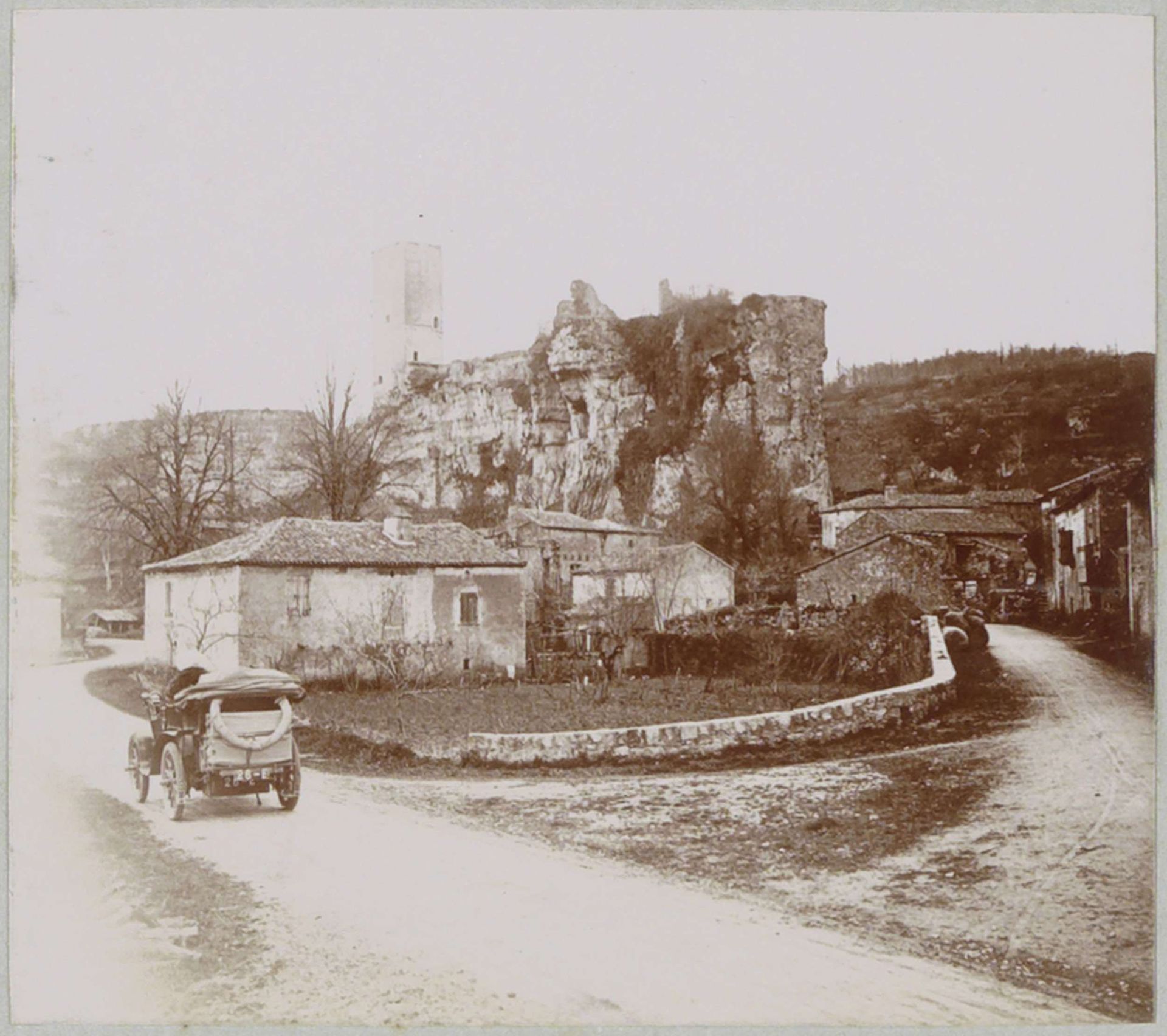 Automobiel op een landweg bij een dorp met een toren, mogelijk in de Dordogne by Delizy