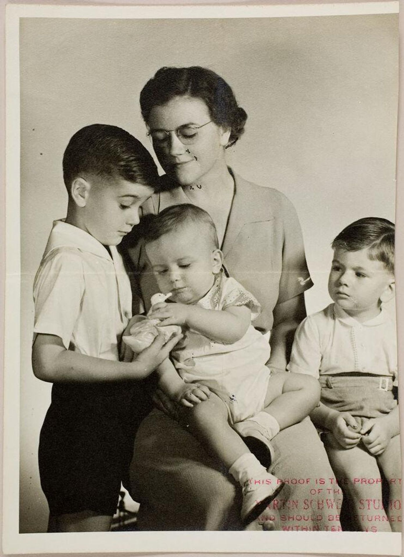 Untitled (studio portrait of woman with two young sons and baby looking at toy duck) by Martin Schweig