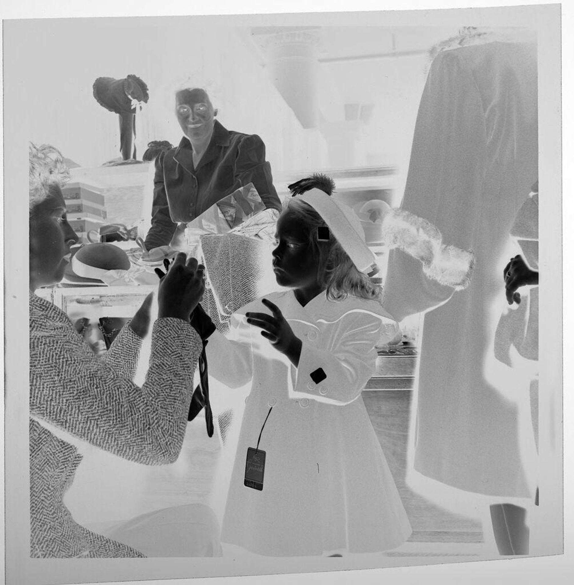 Untitled (child in store trying on gloves, coat, and hat) by Jack Gould