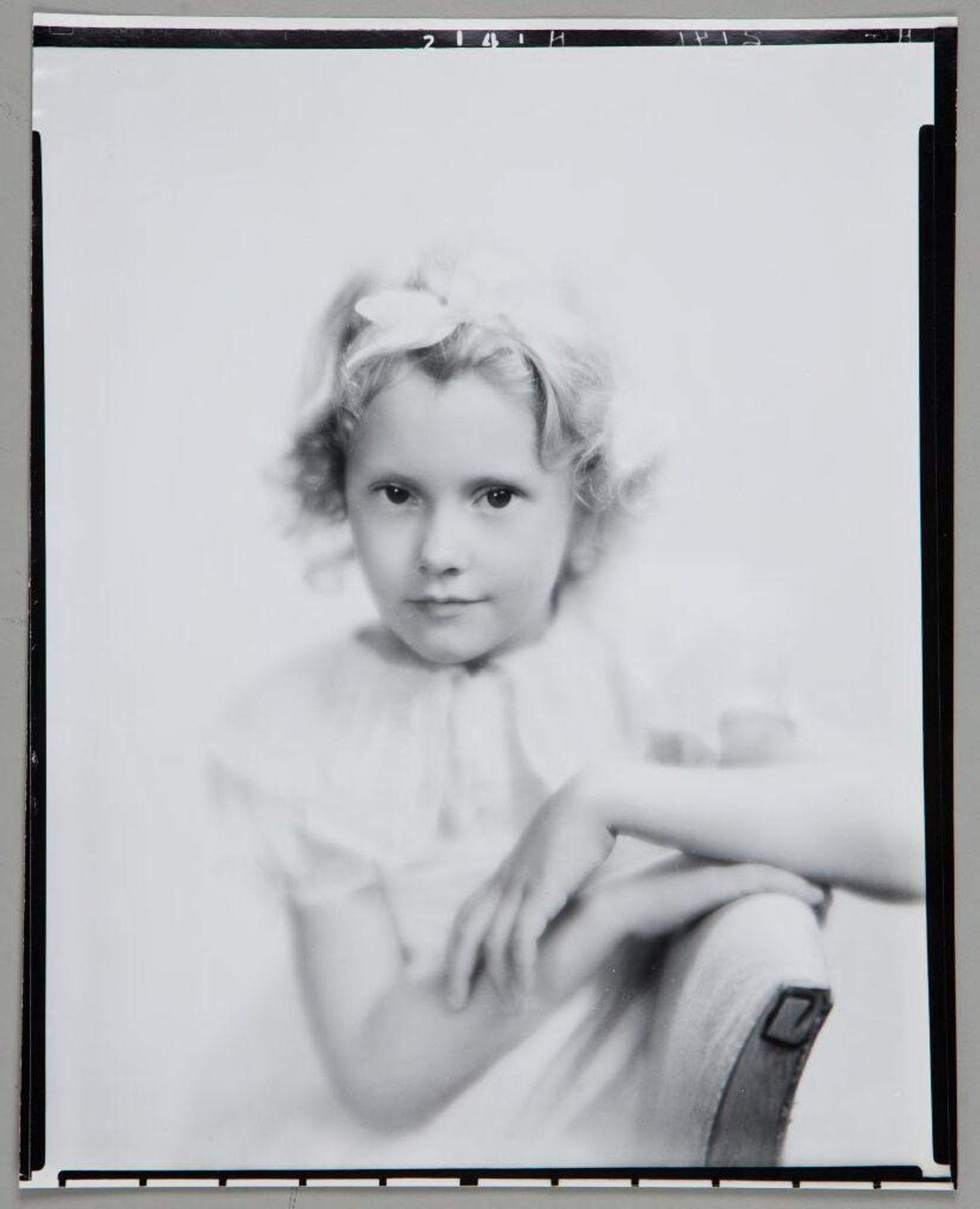 Untitled (portrait of blond girl with bow in hair, arm over back of chair) by Paul Gittings