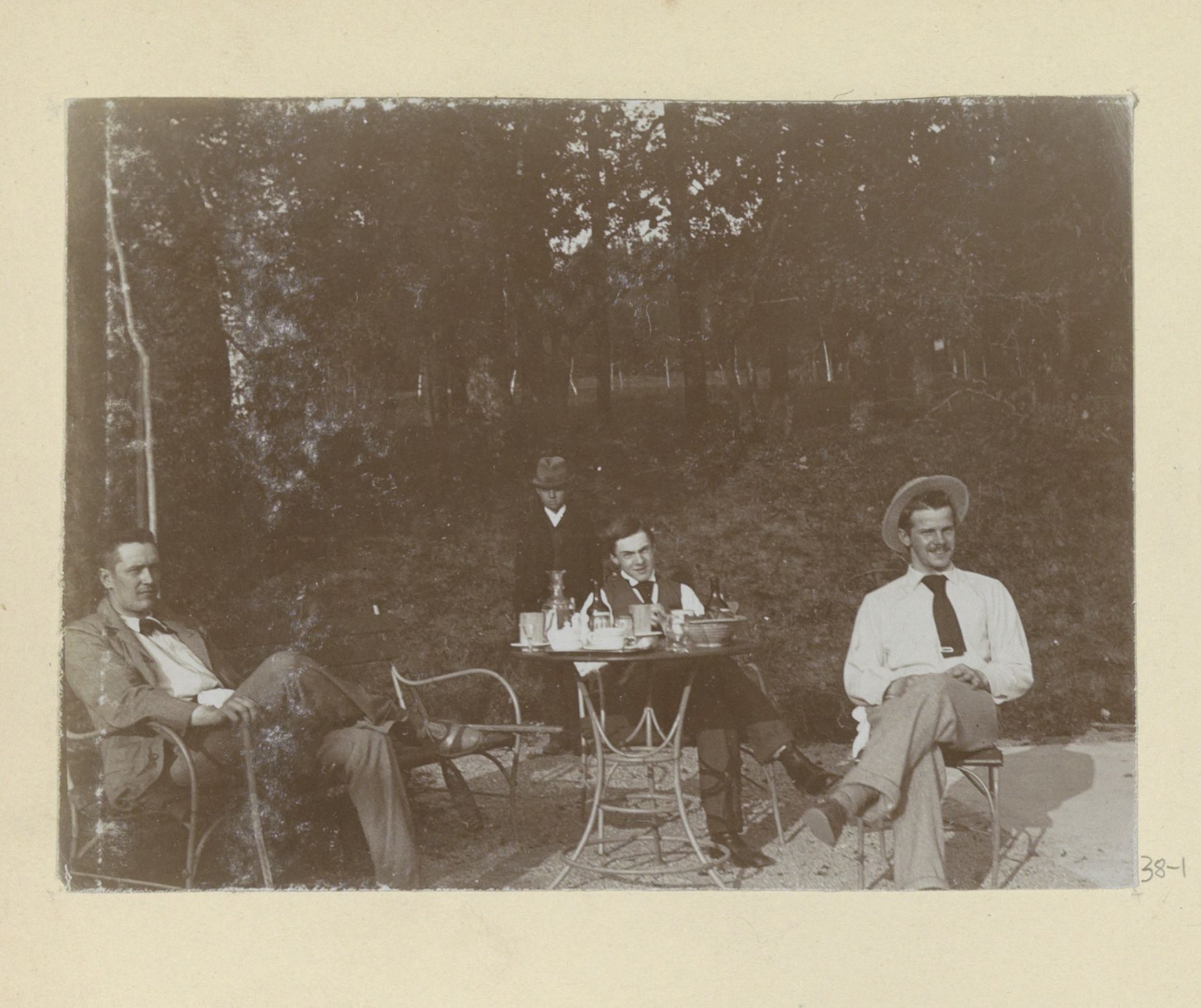 Gezelschap zittend aan tafel naast een tennisbaan by Hendrik Herman van den Berg