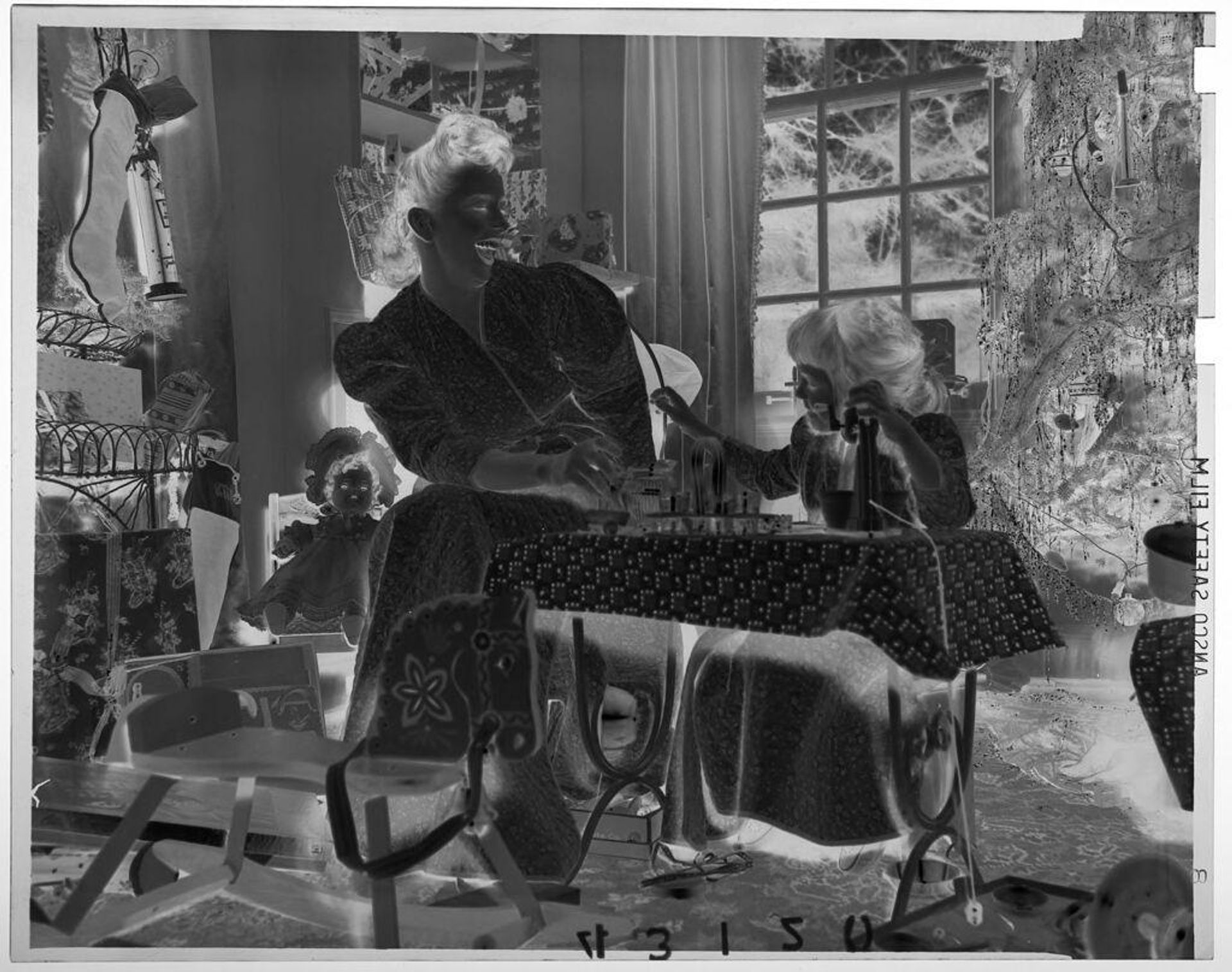 Untitled (young girl sitting in front of toy sewing machine poking woman beside her in room decorated for Christmas) by Martin Schweig