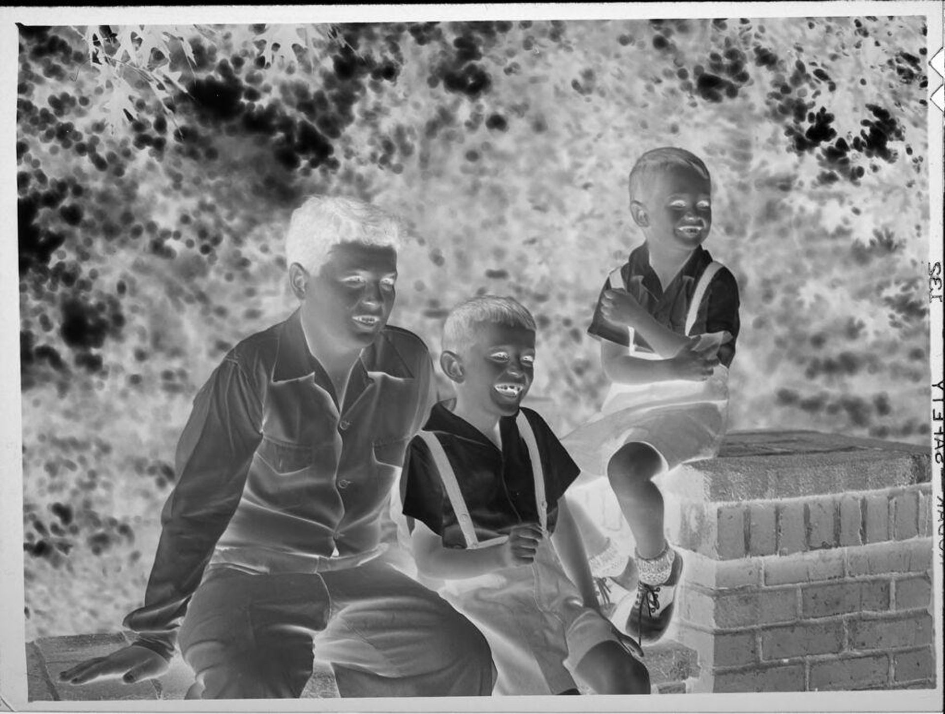 Untitled (three boys on brick wall) by Lucian and Mary Brown