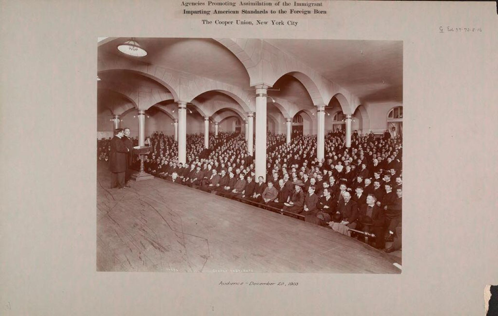 Education, Popular Culture: United States. New York. New York City. Cooper Union: Agencies Promoting Assimilation of the Immigrant. Imparting American Standards to the Foreign Born: The Cooper Union, New York City: Audience - December 20, 1903 by Percy C. Byron
