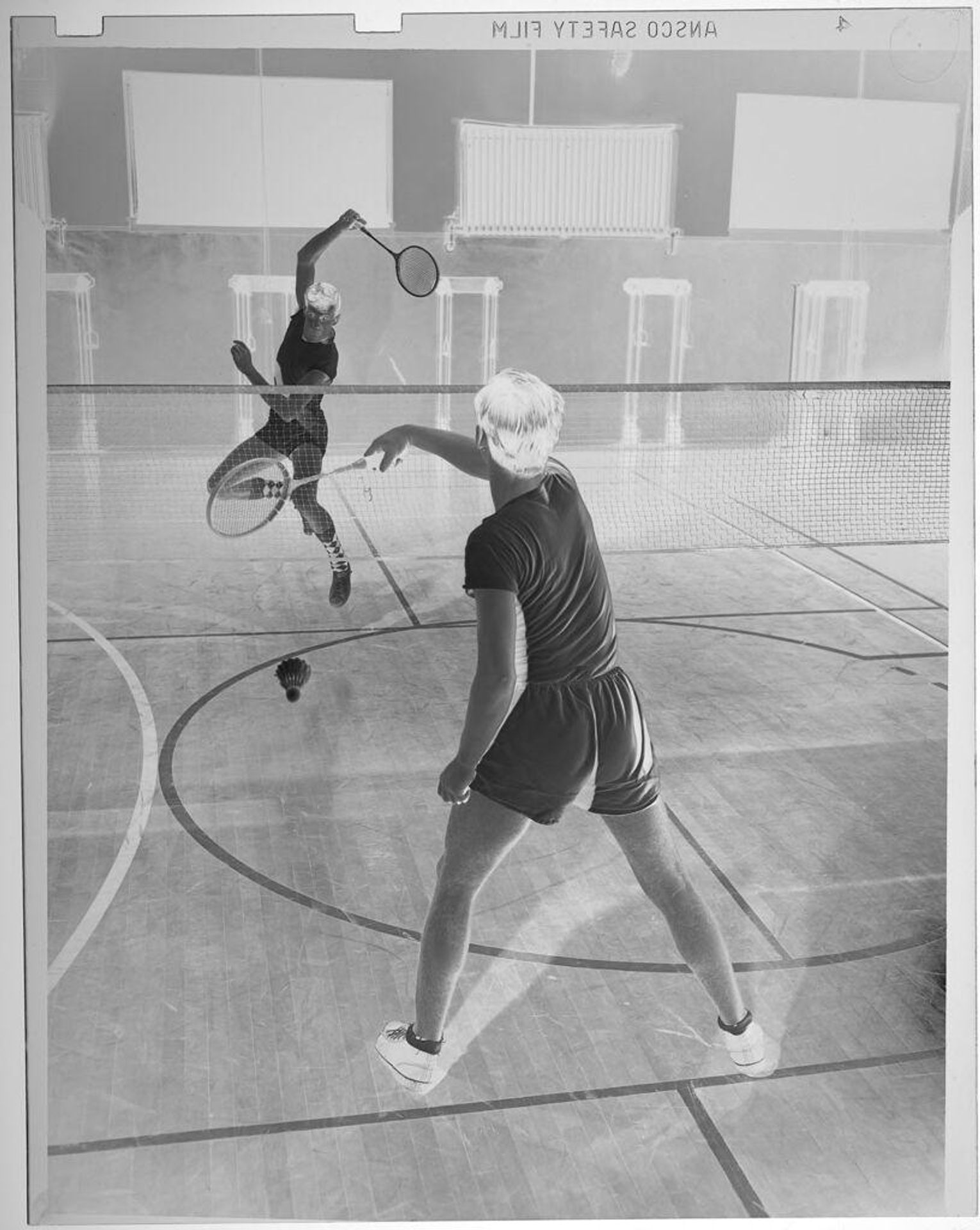 Untitled (two men playing indoor badminton) by Jack Gould