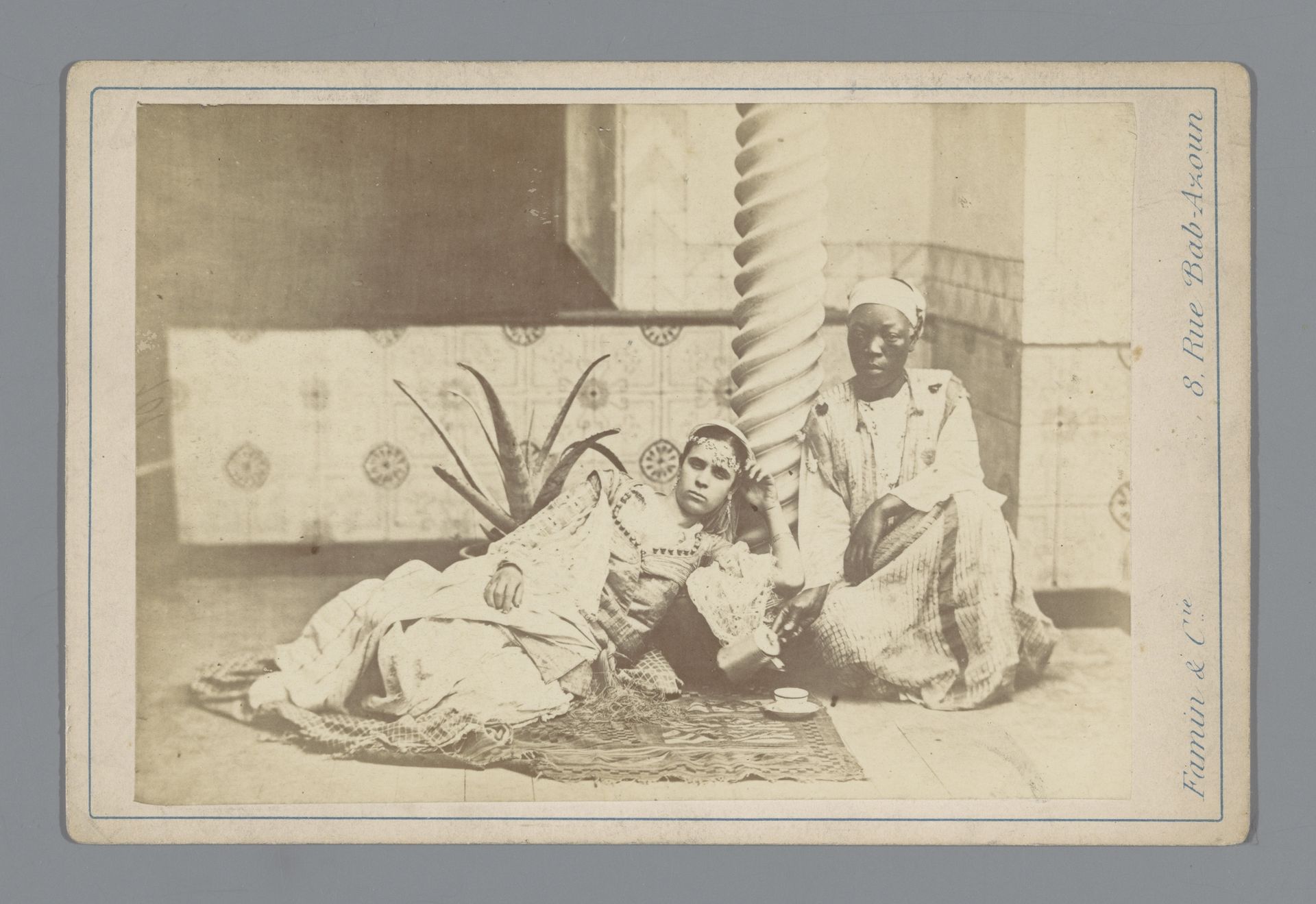 Twee mensen in traditionele kledij bij zuil in Algerije by Famin et Cie.