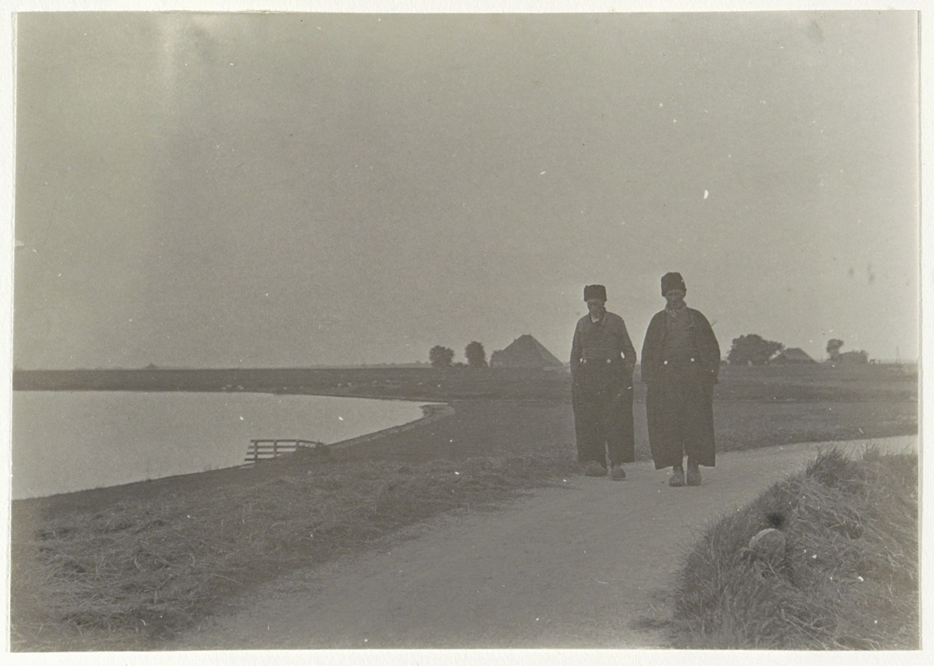 Twee mannen in Volendamse klederdracht lopend op een dijk by G. Hidderley