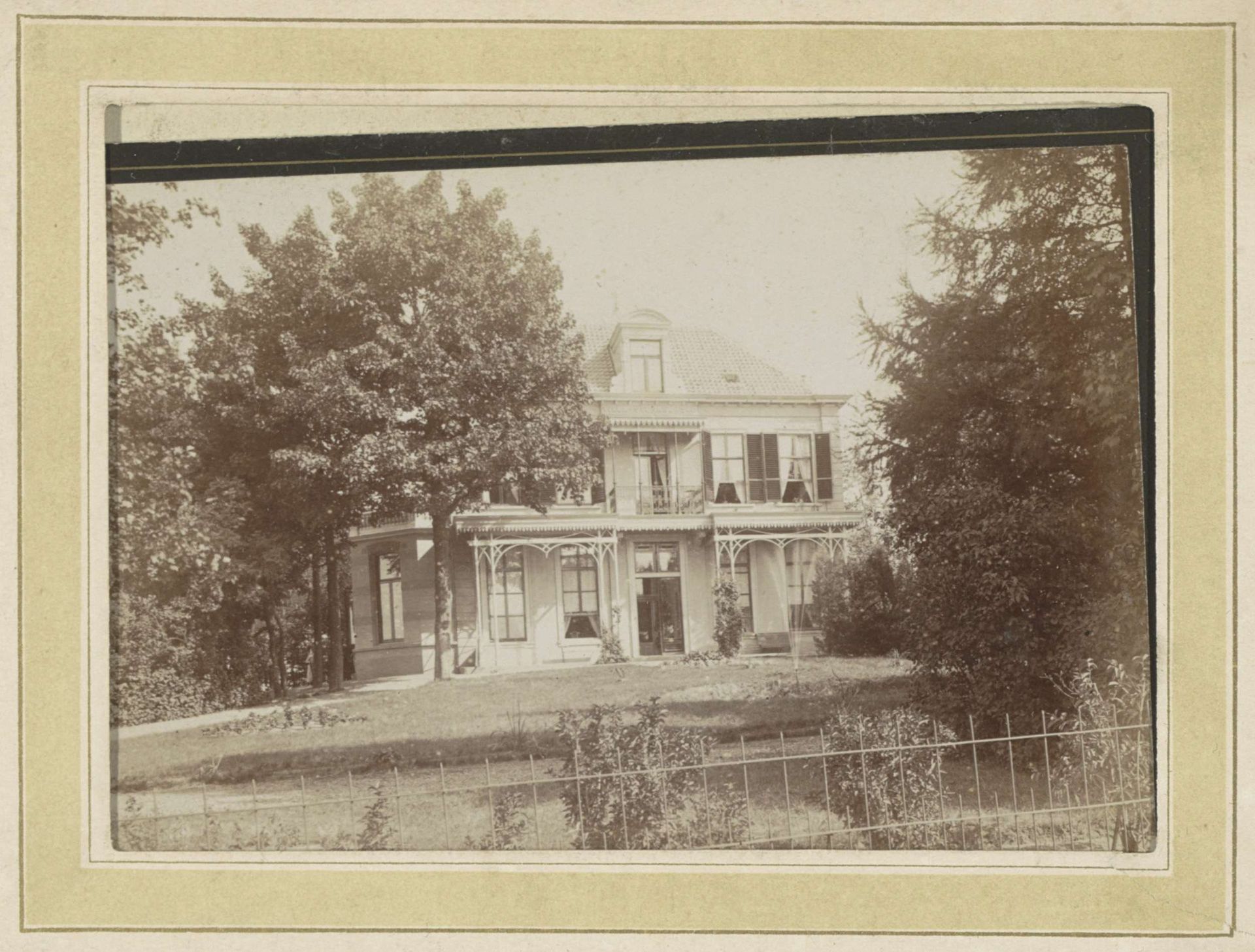 Exterieur van een villa met veranda en voortuin achter een hek by Brainich & Leusink