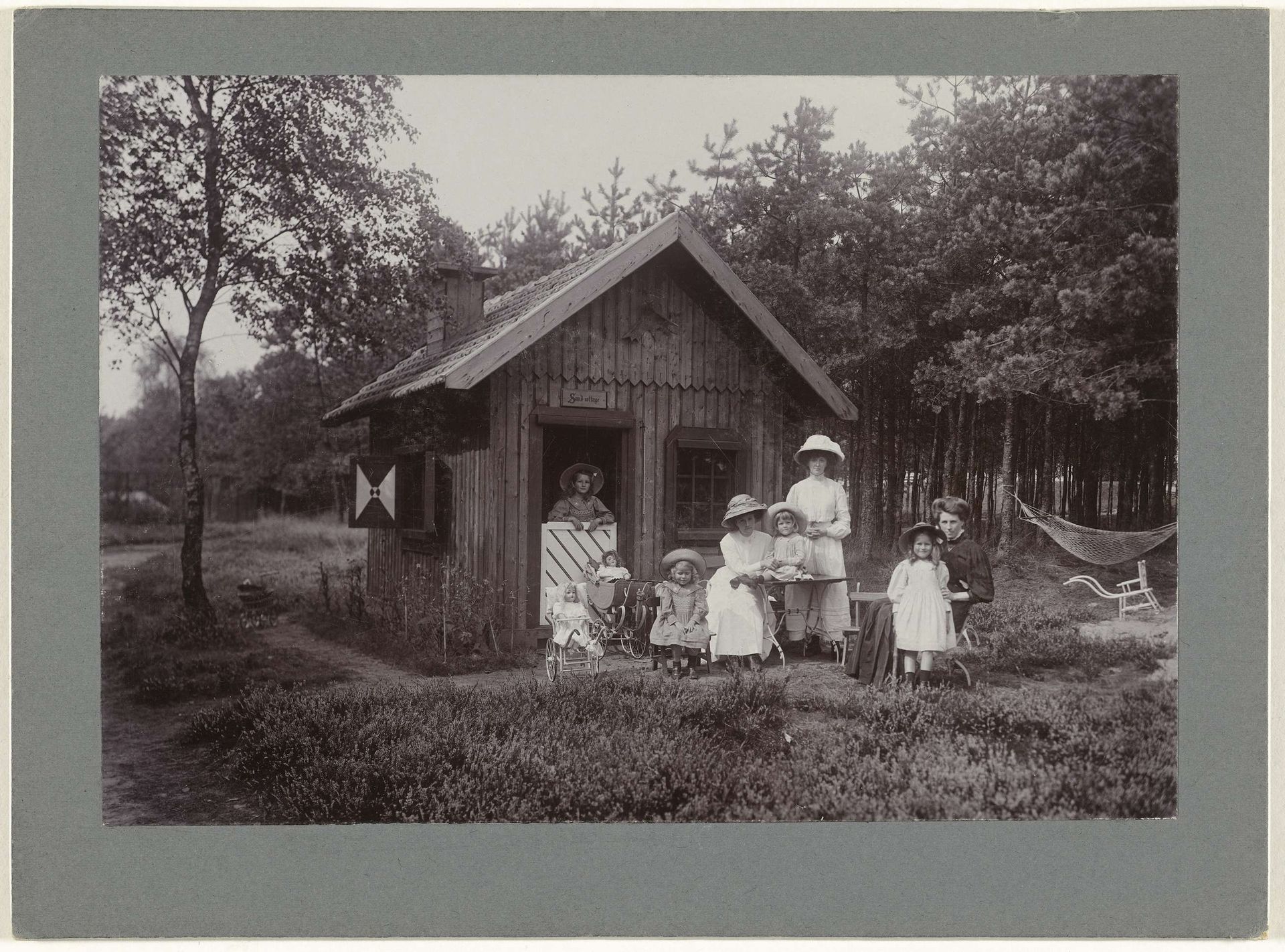 De kinderen van de fotograaf(Renée, Thelma, Irène en Sacha) met hun moeder en twee nannies en moeder bij een speelhuis (?), 'Sand cottage' by Henry Pauw van Wieldrecht