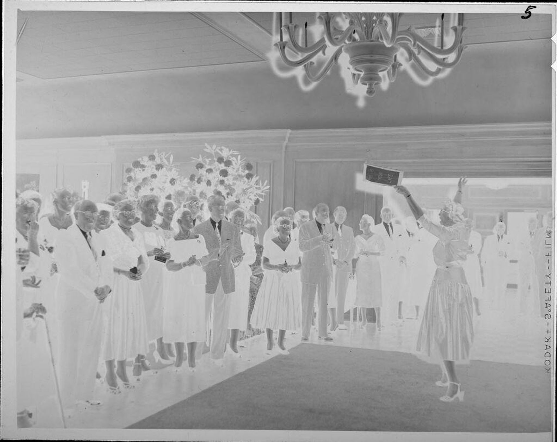 Untitled (woman holding book, in front of large group) by Lucian and Mary Brown