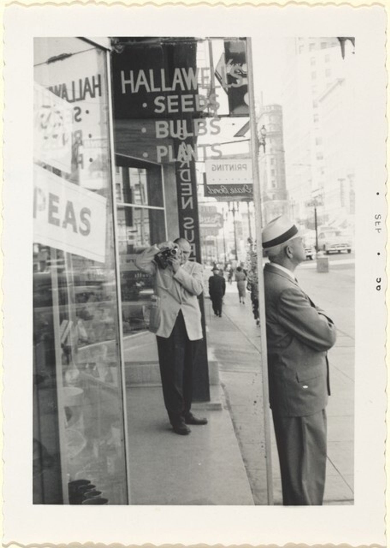 Untitled (Man on street taking pictures of himself in mirror) by Anonymous