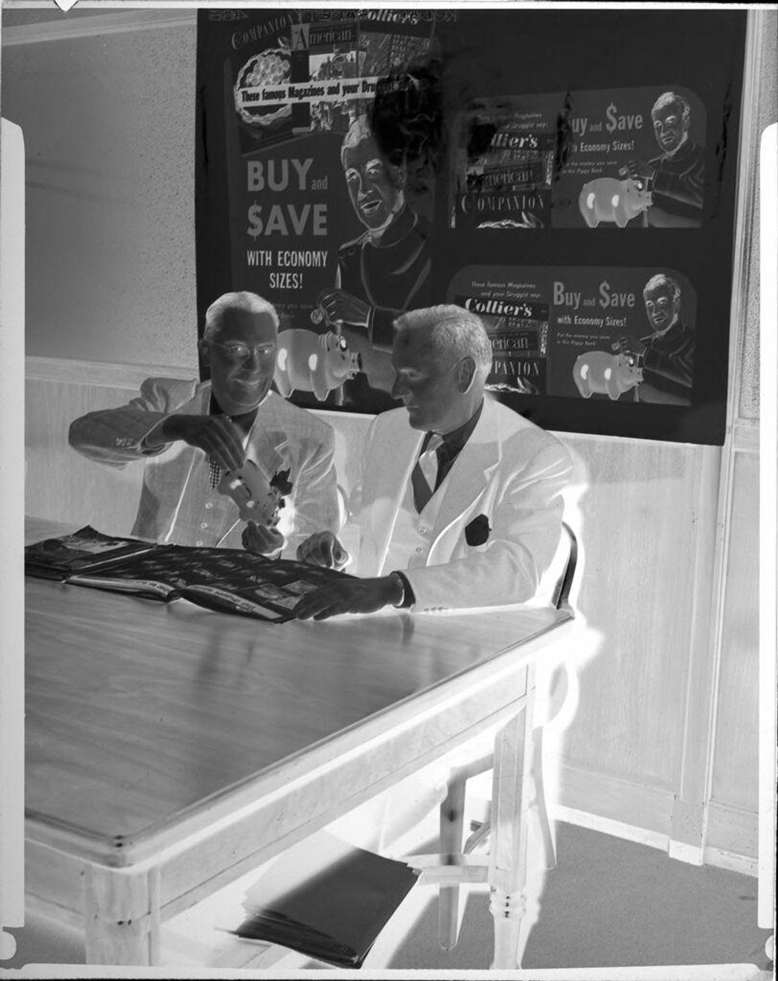 Untitled (two men with piggy bank in front of posters) by Peter James Studio